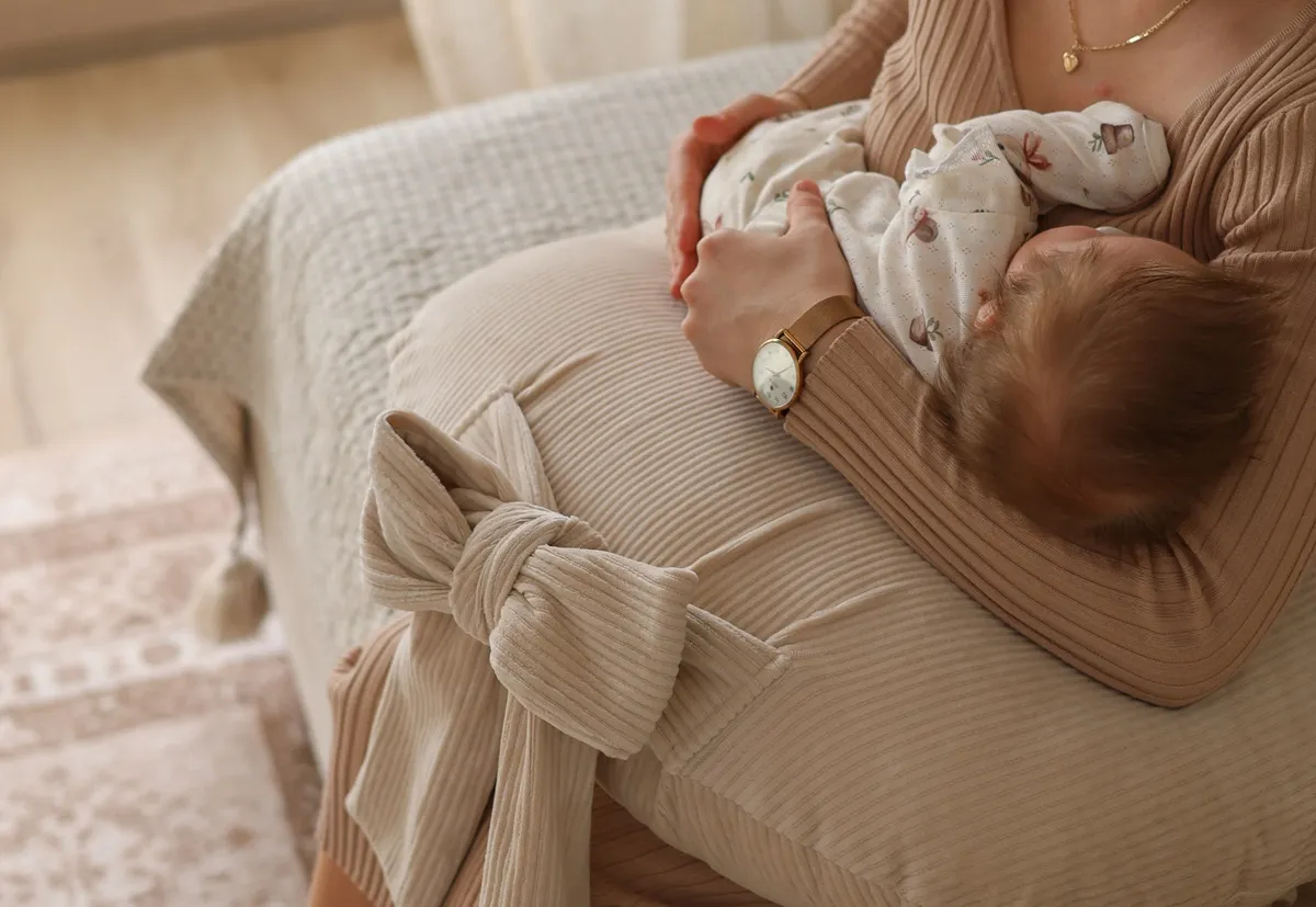 niemowlę leżące na brzuszku na poduszce rogalu