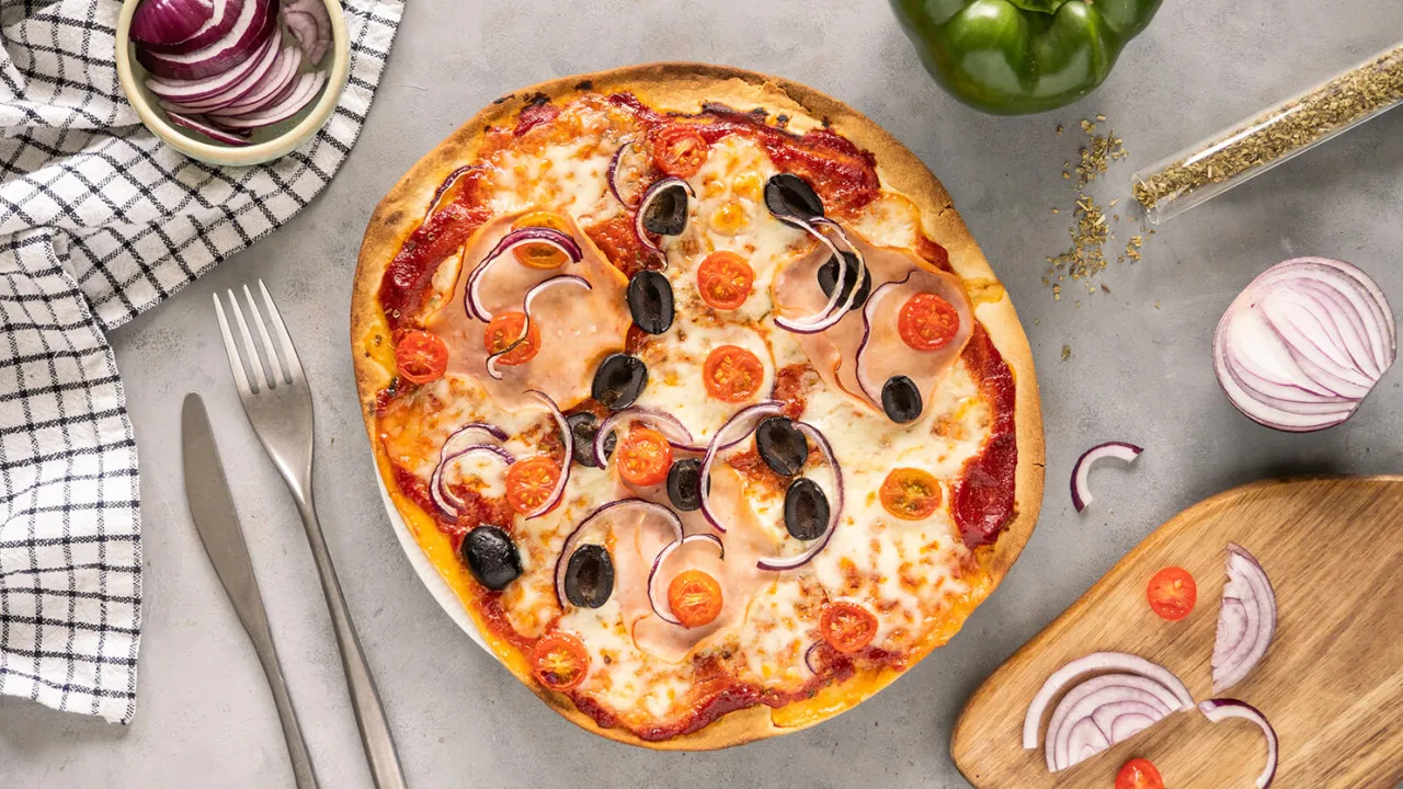 Domowa pizza z szynką, oliwkami i pomidorkami. Zastanawiasz się, ile kcal ma domowa pizza? Ta wygląda pysznie!