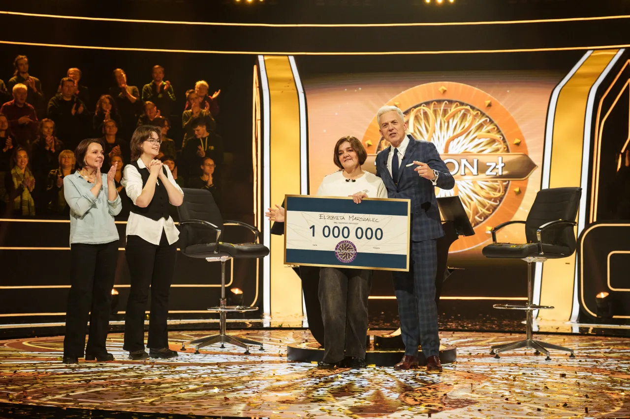 Elżbieta Marszalec wygrała milion w programie Milionerzy! W tle widać publiczność i prowadzącego.