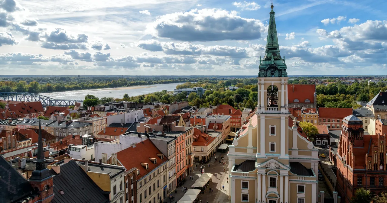Widok na Toruń, jedno z najpiękniejszych miejsc Kujawsko-Pomorskiego. Widać Wisłę, most i zabytkową architekturę.
