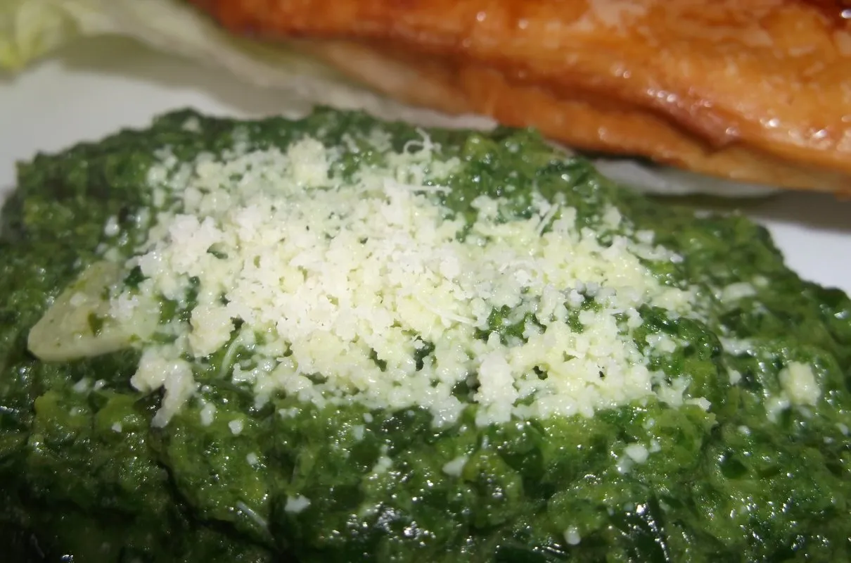 Jak przyrządzić szpinak mrożony brykiet? Oto pyszny, kremowy szpinak z czosnkiem i parmezanem, gotowy do podania.