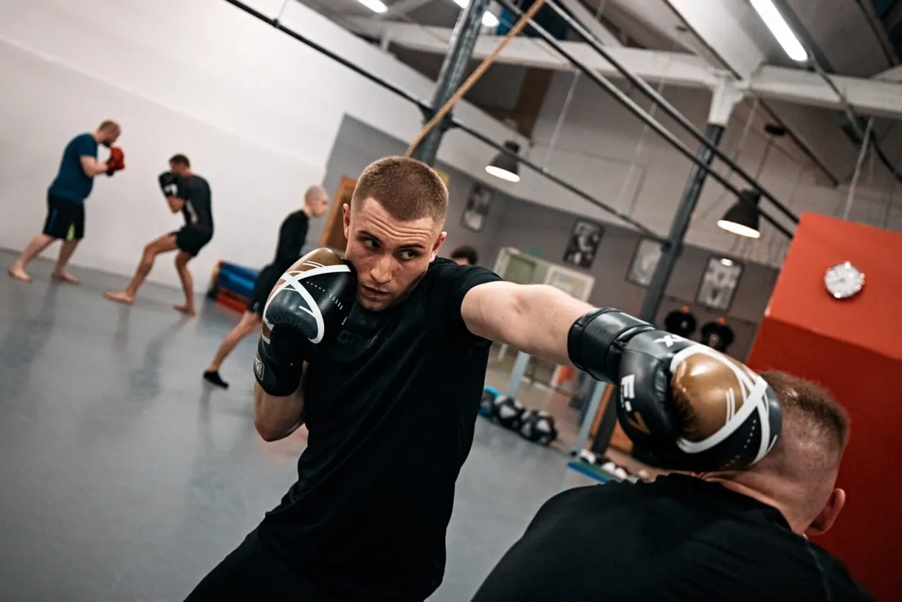 Intensywny trening bokserski w Łodzi. Mężczyzna w rękawicach wyprowadza cios. Idealne miejsce, gdzie trenować crossfit w Łodzi.