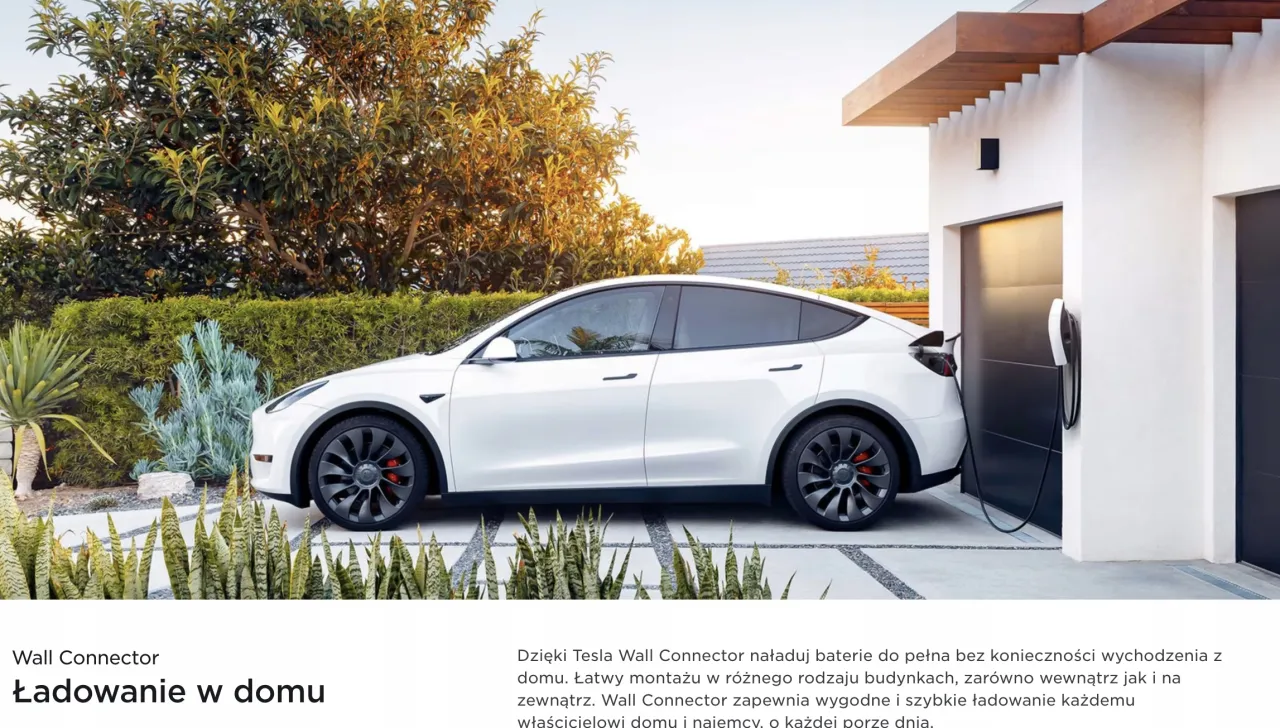 Biała Tesla Model Y ładuje się przy domu. Zastanawiasz się, ile kosztuje najtańsza Tesla?