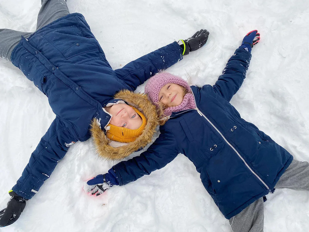 Dzieci leżą na śniegu, tworząc aniołki. Pamiętaj o bezpieczne ferie zasady, by zabawa była udana!