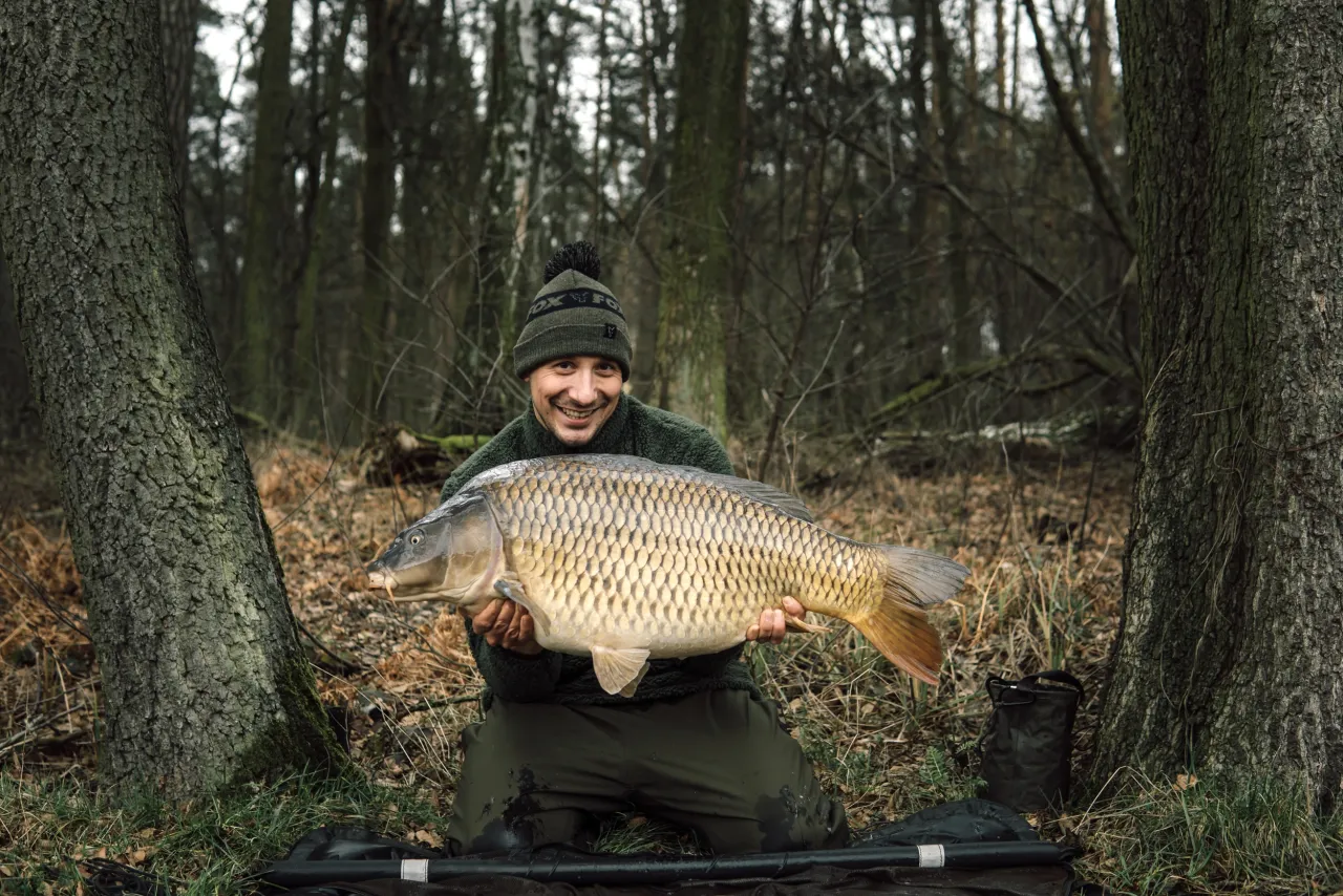 Szczęśliwy wędkarz z okazałym karpiem, złowionym w lesie, gdzie jest łowisko maślanka.