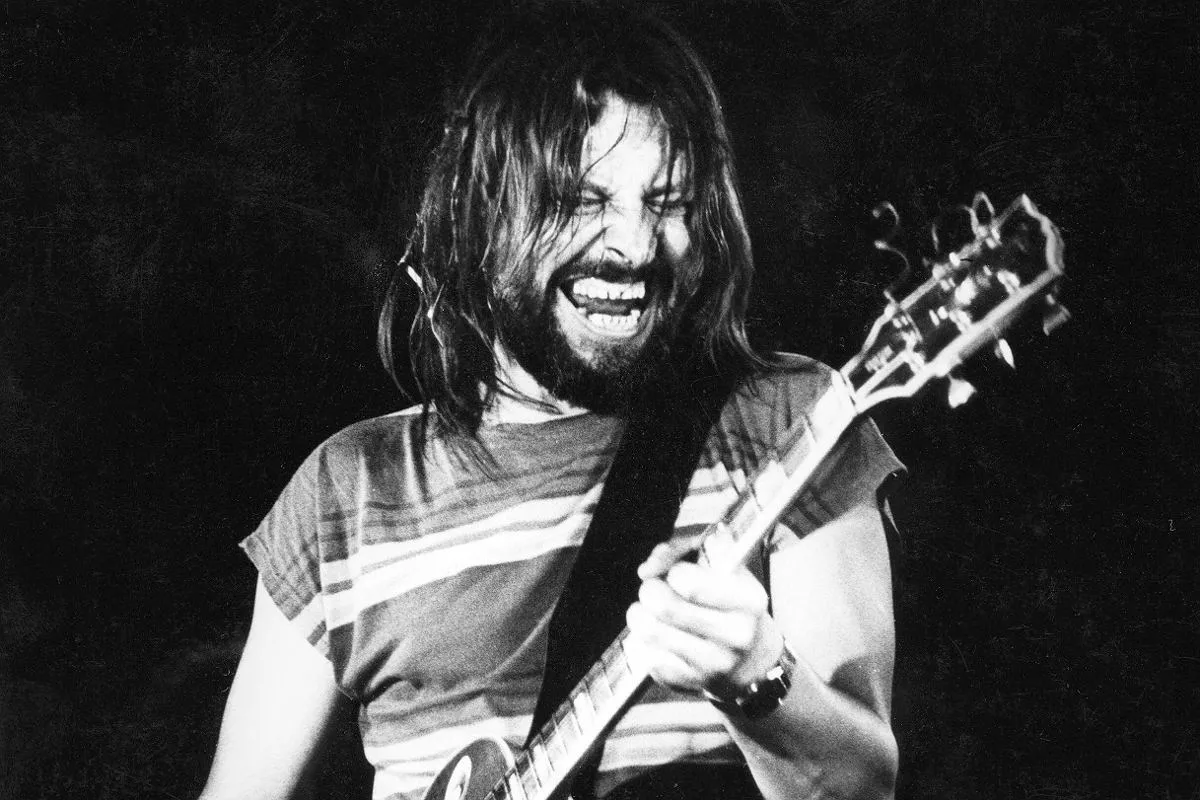 Mężczyzna z brodą i długimi włosami gra na gitarze, krzycząc z pasją. To jak tekst piosenki, kiedy byłem małym chłopcem, pełen energii.