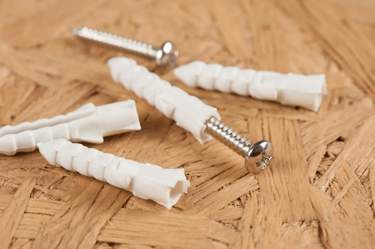 Kołki rozporowe i wkręty na drewnianym tle. Podstawa do zrozumienia, jak zamontować regał.