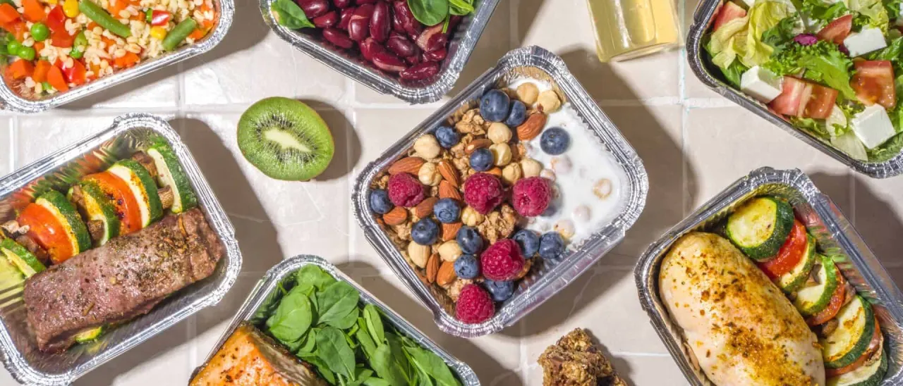 Różnorodne posiłki w pojemnikach: łosoś, kurczak, wołowina z warzywami, sałatka, fasola, granolą z owocami. Zastanawiasz się, ile kosztuje catering na miesiąc dla jednej osoby?