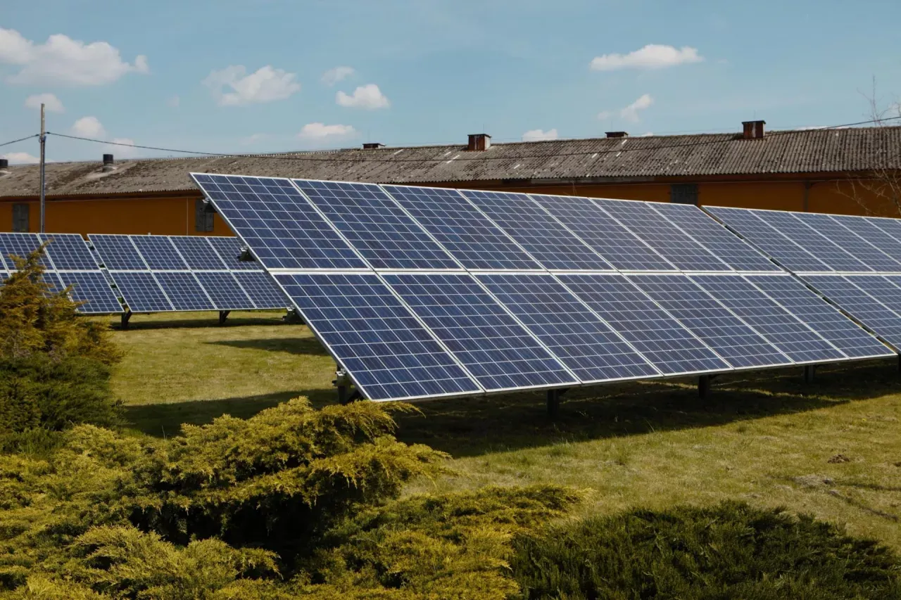 Panele fotowoltaiczne na tle budynku gospodarczego. Nowelizacja ustawy o OZE sprzyja takim inwestycjom.