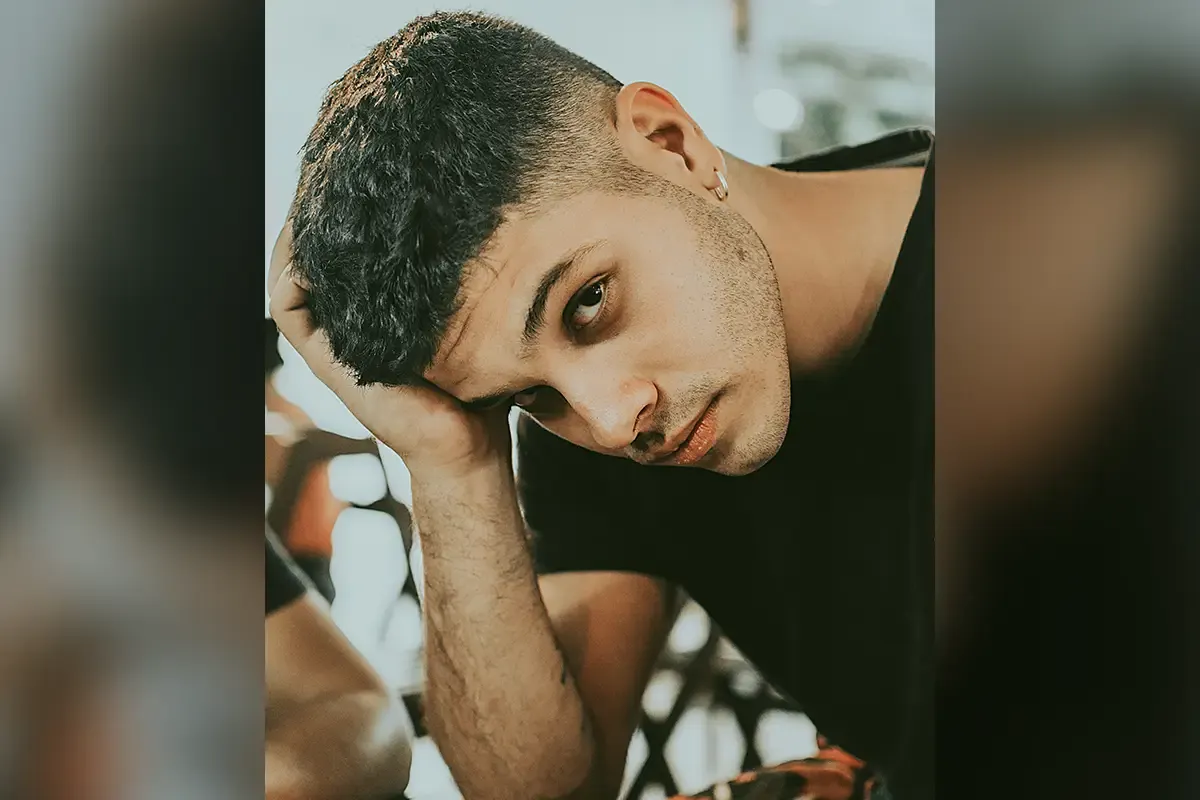 Młody mężczyzna z modną fryzurą, kt&oacute;ra dodaje mu uroku. Kr&oacute;tkie włosy z wycieniowanymi bokami to jedne z fryzur męskich kt&oacute;re odmładzają.