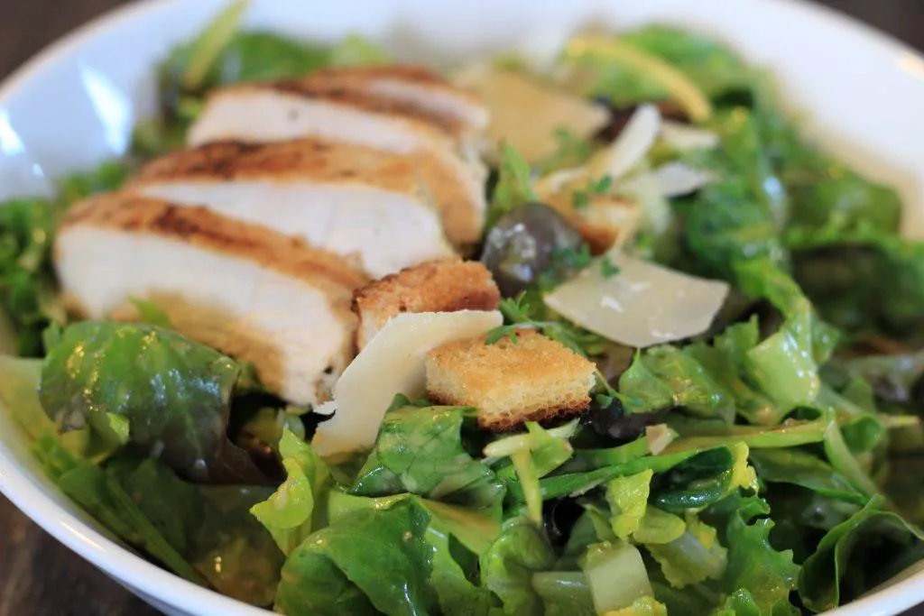 Caesar Salad mit gegrillter H&auml;hnchenbrust und Parmesan Sp&auml;nen in einer Sch&uuml;ssel