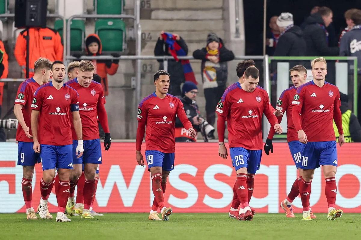 Zawodnicy Rakowa Częstochowa w czerwonych koszulkach i niebieskich spodenkach idą po boisku.