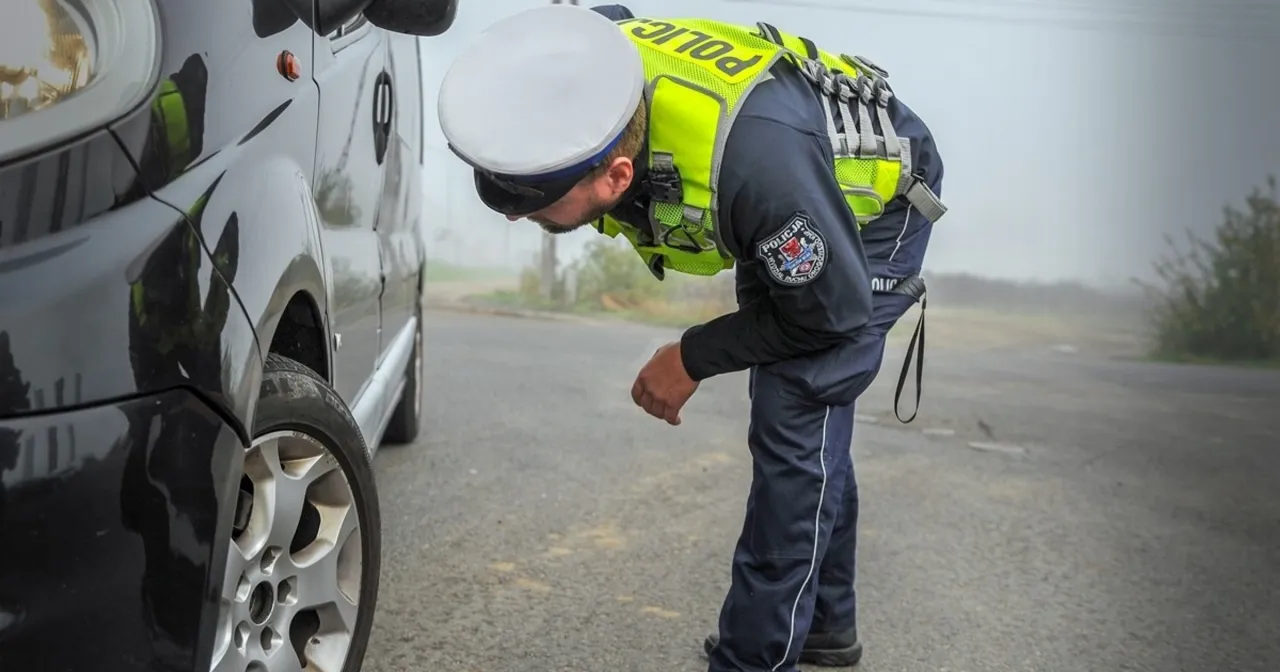 Policjant kontrolujący bieżnik opony zimą