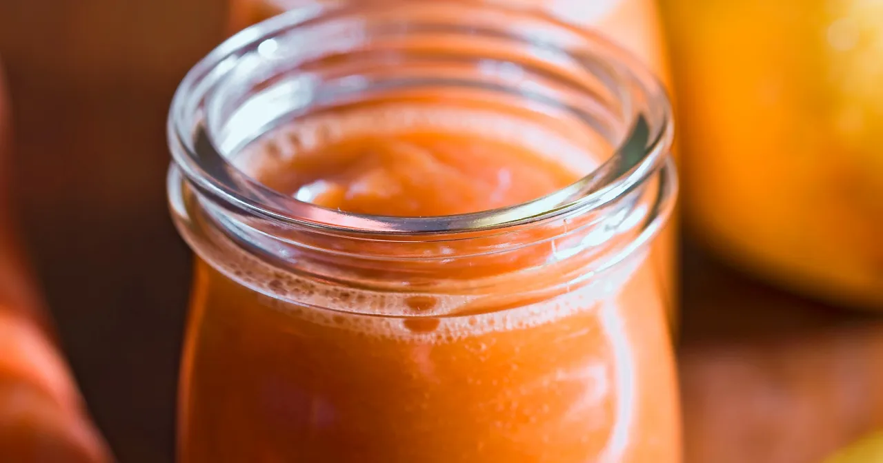 Pomarańczowy mus owocowy w szklanym słoiczku. Czy musy owocowe są lekkostrawne? Ten wygląda na pyszny i zdrowy.