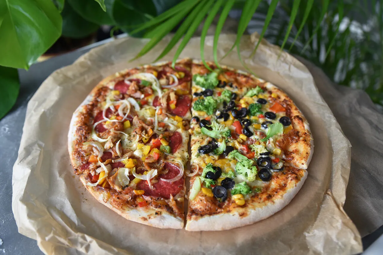 Pizza podzielona na p&oacute;ł, z r&oacute;żnymi dodatkami. Zastanawiasz się, ile kawałk&oacute;w ma pizza? Ta ma ich 8!