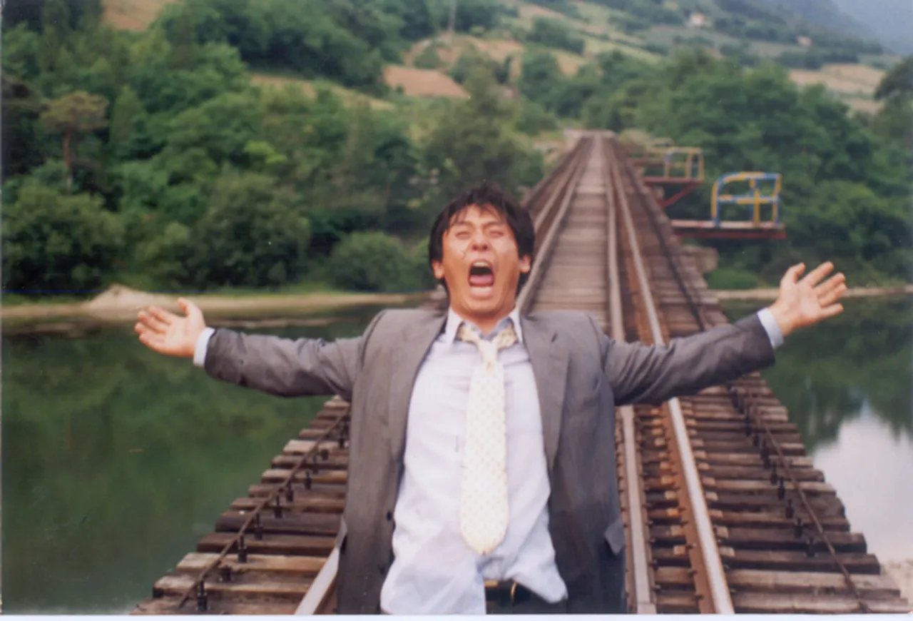 Mężczyzna w garniturze krzyczy na torach kolejowych, rozkładając ramiona. To scena jak z filmu Lee Chang Dong.