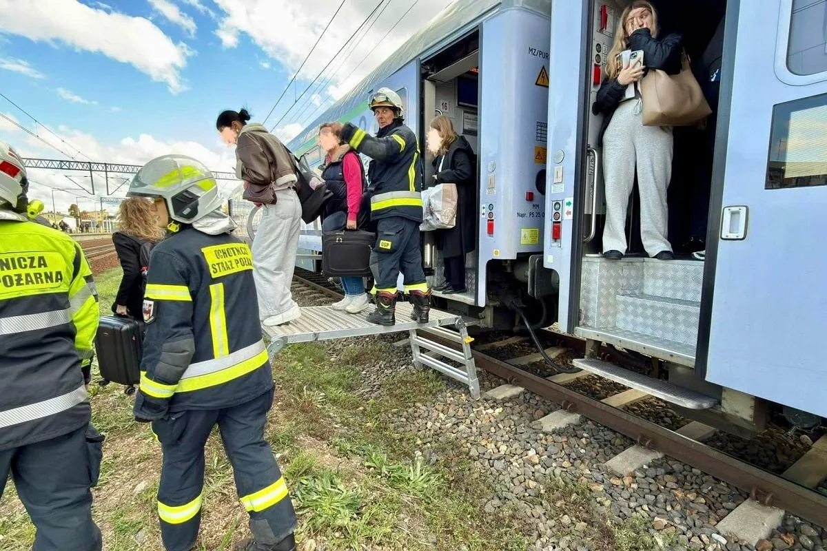Warszawa awaria pociągów: Strażacy pomagają pasażerom wysiadać z pociągu po awarii.