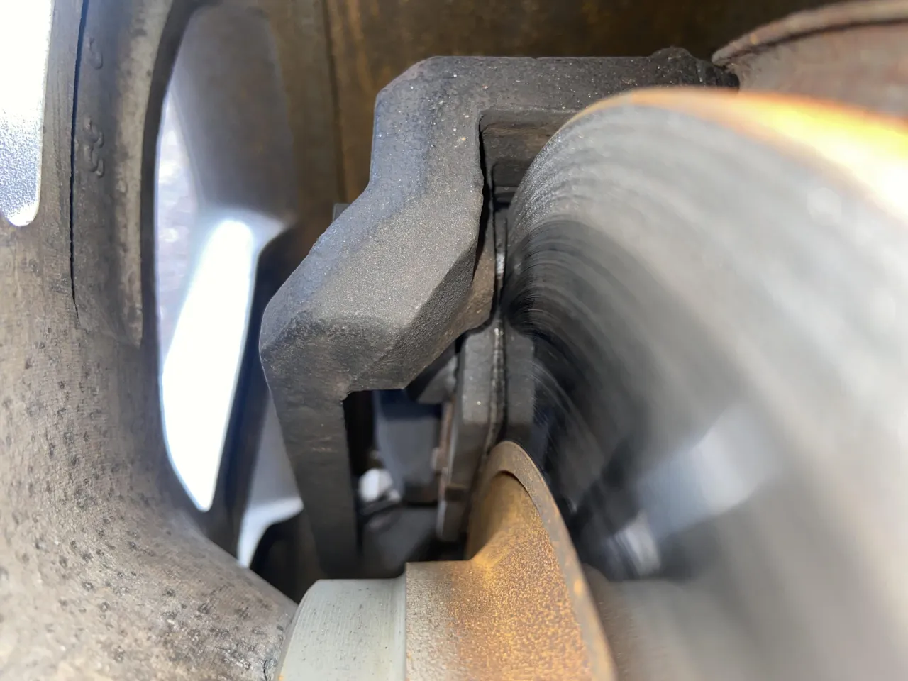 Zbliżenie na tarczę hamulcową i zacisk. Widać zużycie, co wpływa na żywotność klock&oacute;w hamulcowych.