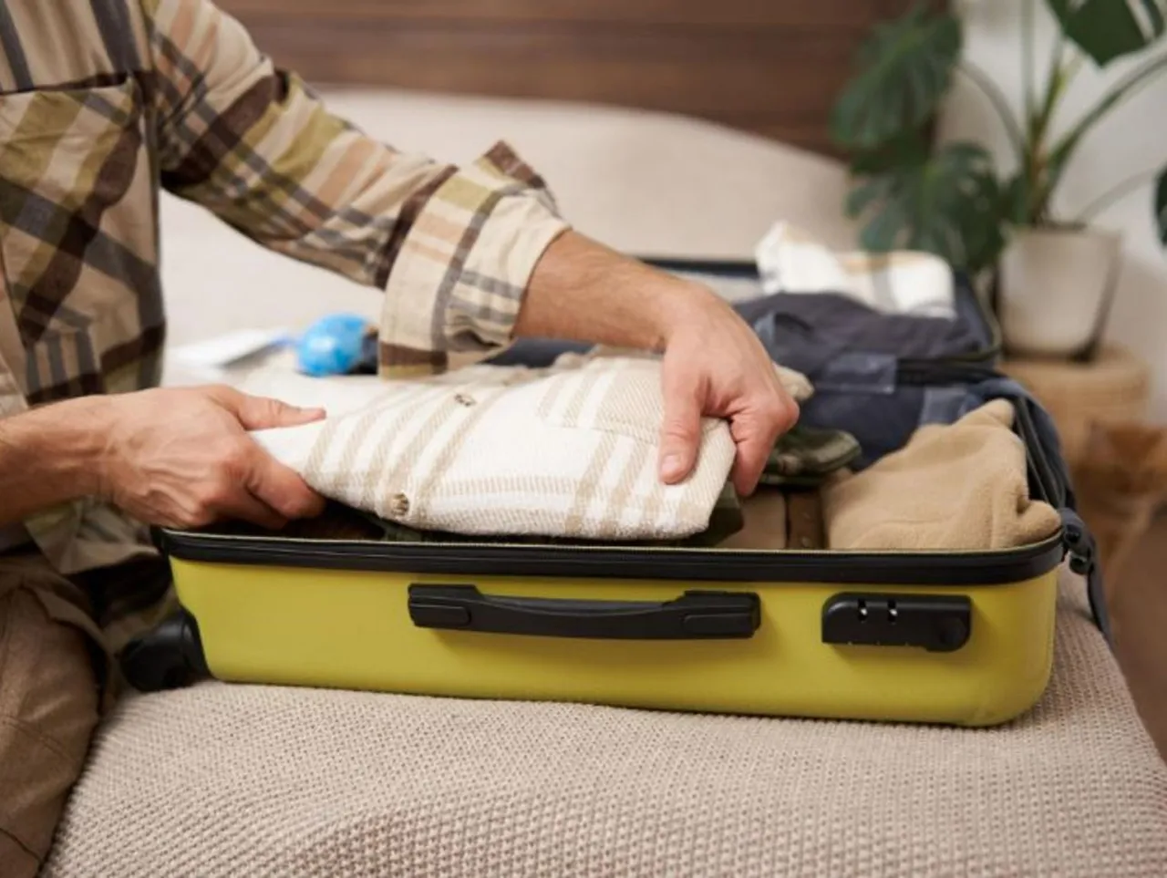 Pakowanie walizki na wyjazd do sanatorium. Widać ubrania, w tym koszulę w kratę, i inne rzeczy.