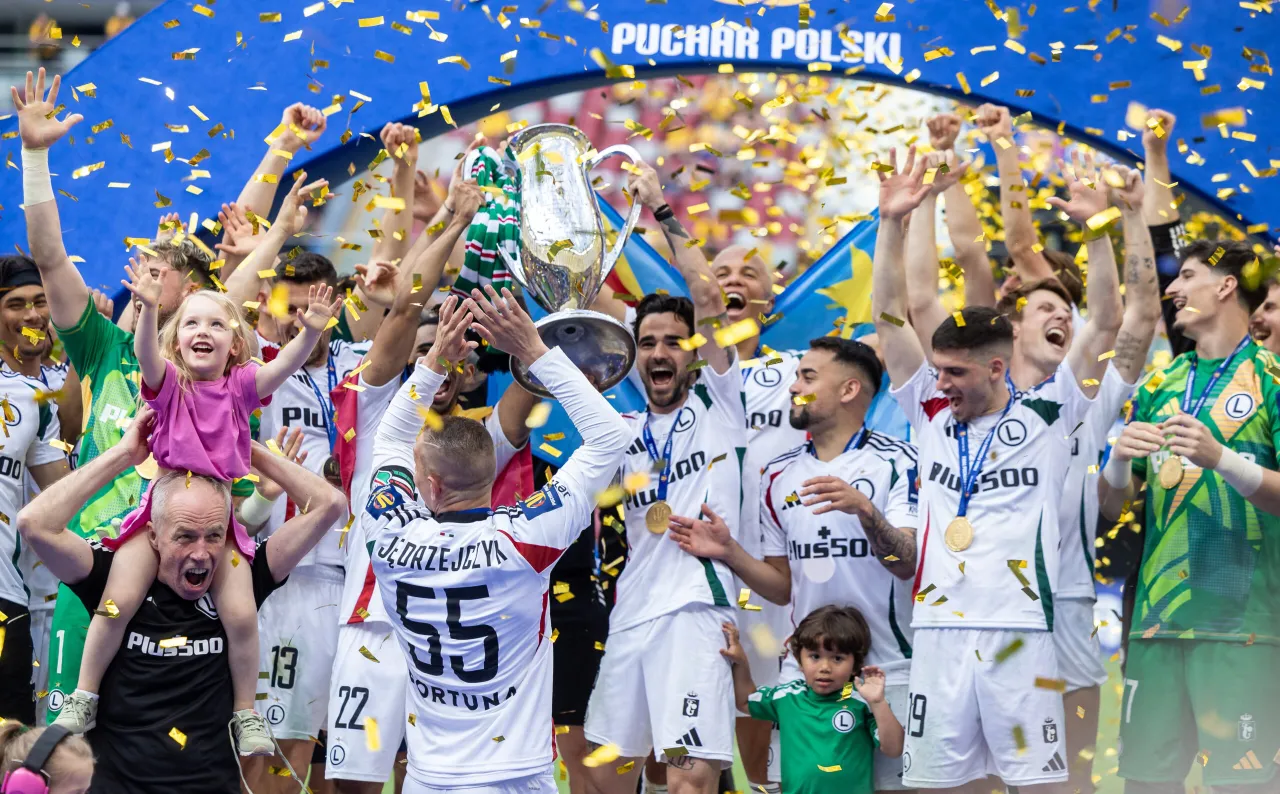 Piłkarze świętują zwycięstwo w Pucharze Polski, unosząc trofeum wśr&oacute;d złotych konfetti.