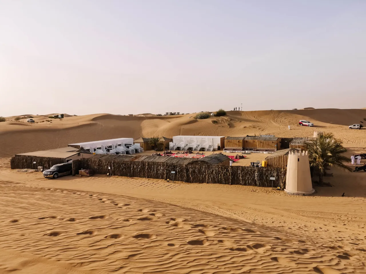 Oaza w pustynnym krajobrazie, gdzie leży Dubaj. Kemping z namiotami i samochodami terenowymi, idealny na safari.