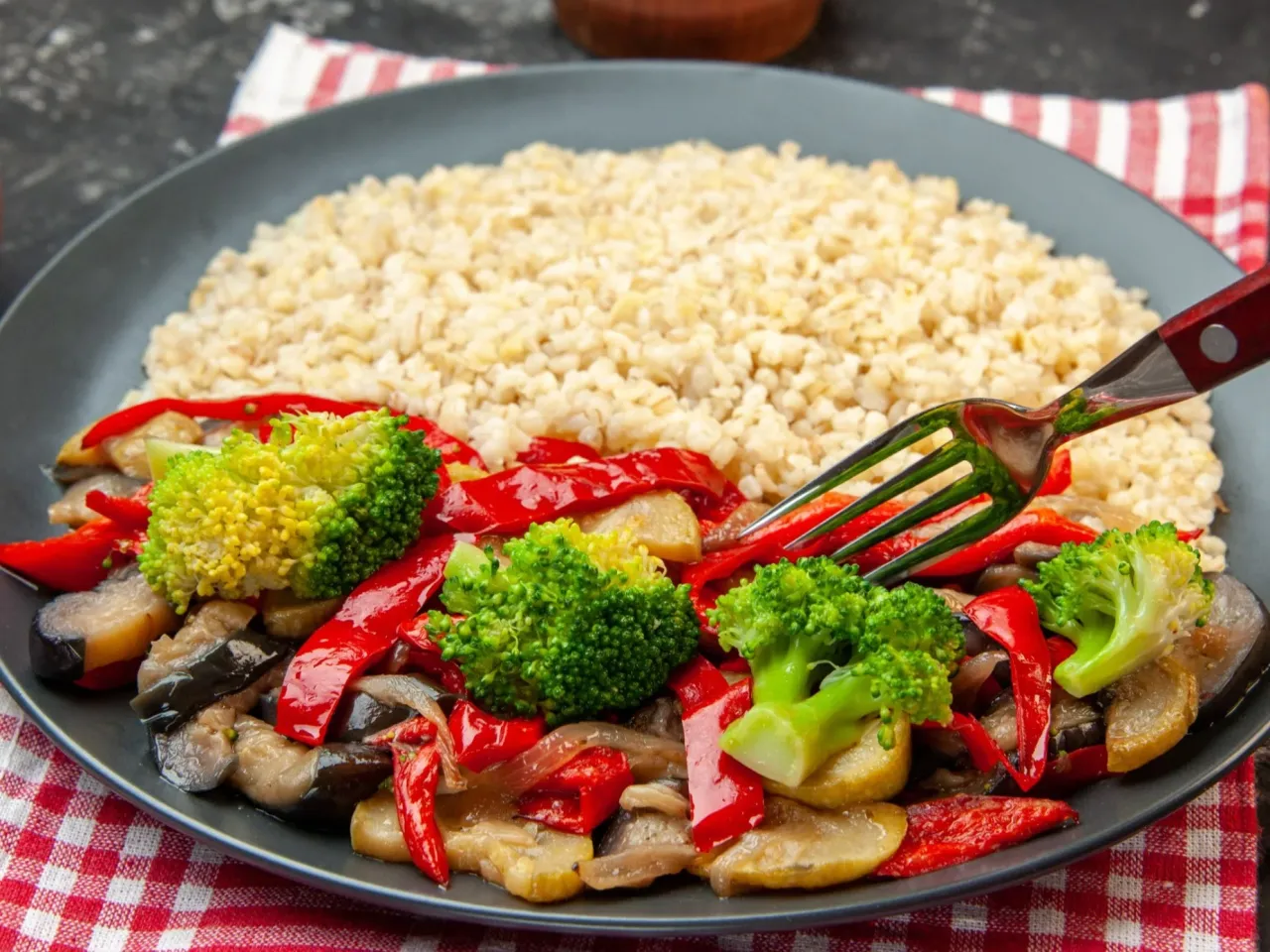 Talerz pełen warzyw z ryżem. Zastanawiasz się, co lepiej na obiad ryż czy ziemniaki na diecie? Ten posiłek z brokułami, papryką i bakłażanem wygląda zdrowo.
