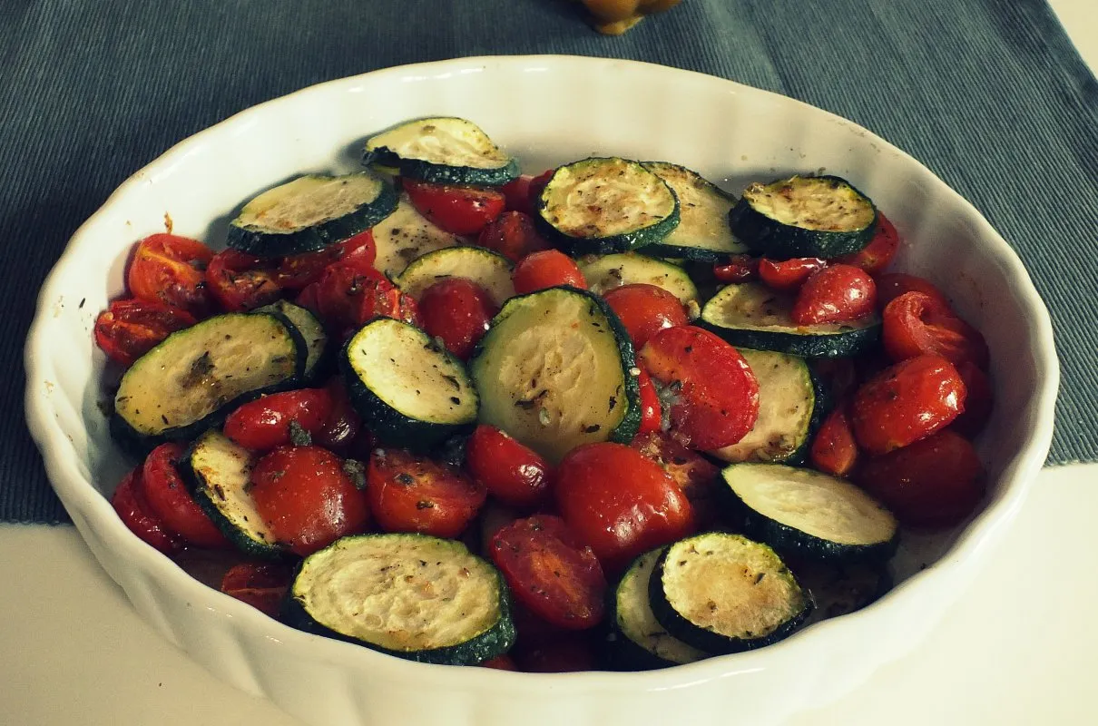 świeże pomidory koktajlowe i cukinia na desce do krojenia