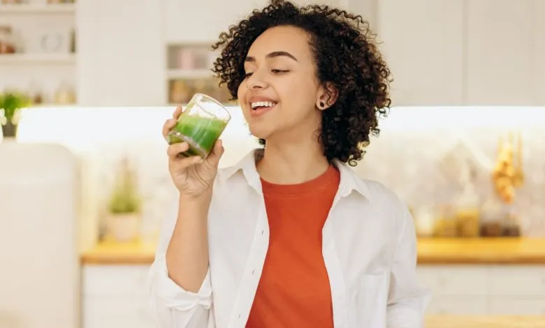 kobieta pijąca zielony koktajl z uśmiechem