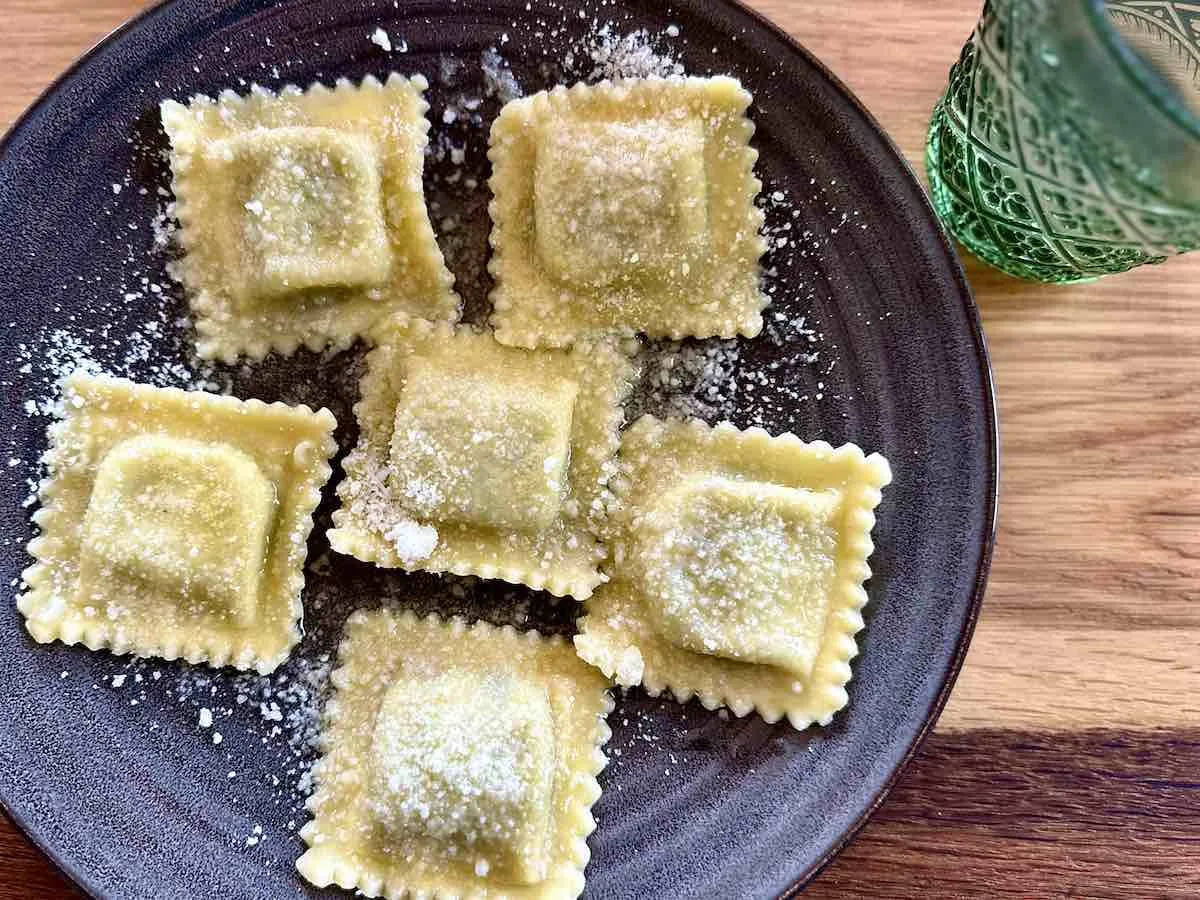 Pięć świeżych ravioli z ricottą i szpinakiem, posypanych parmezanem. Idealne do wypróbowania przepisu!