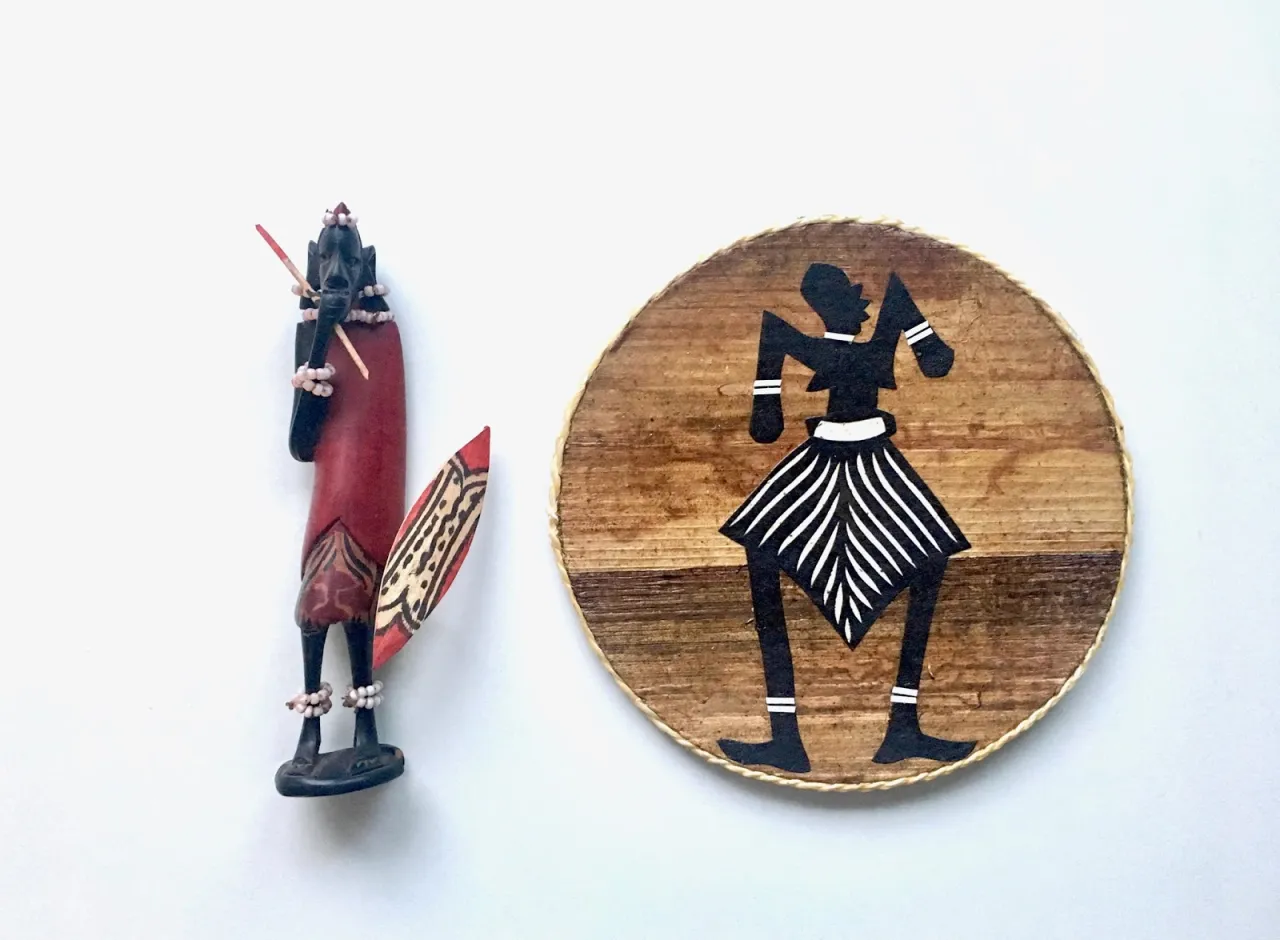 Drewniana figurka wojownika i okrągły medalion z sylwetką tańczącej postaci. Idealne pamiątki, które można przywieźć z Kenii.