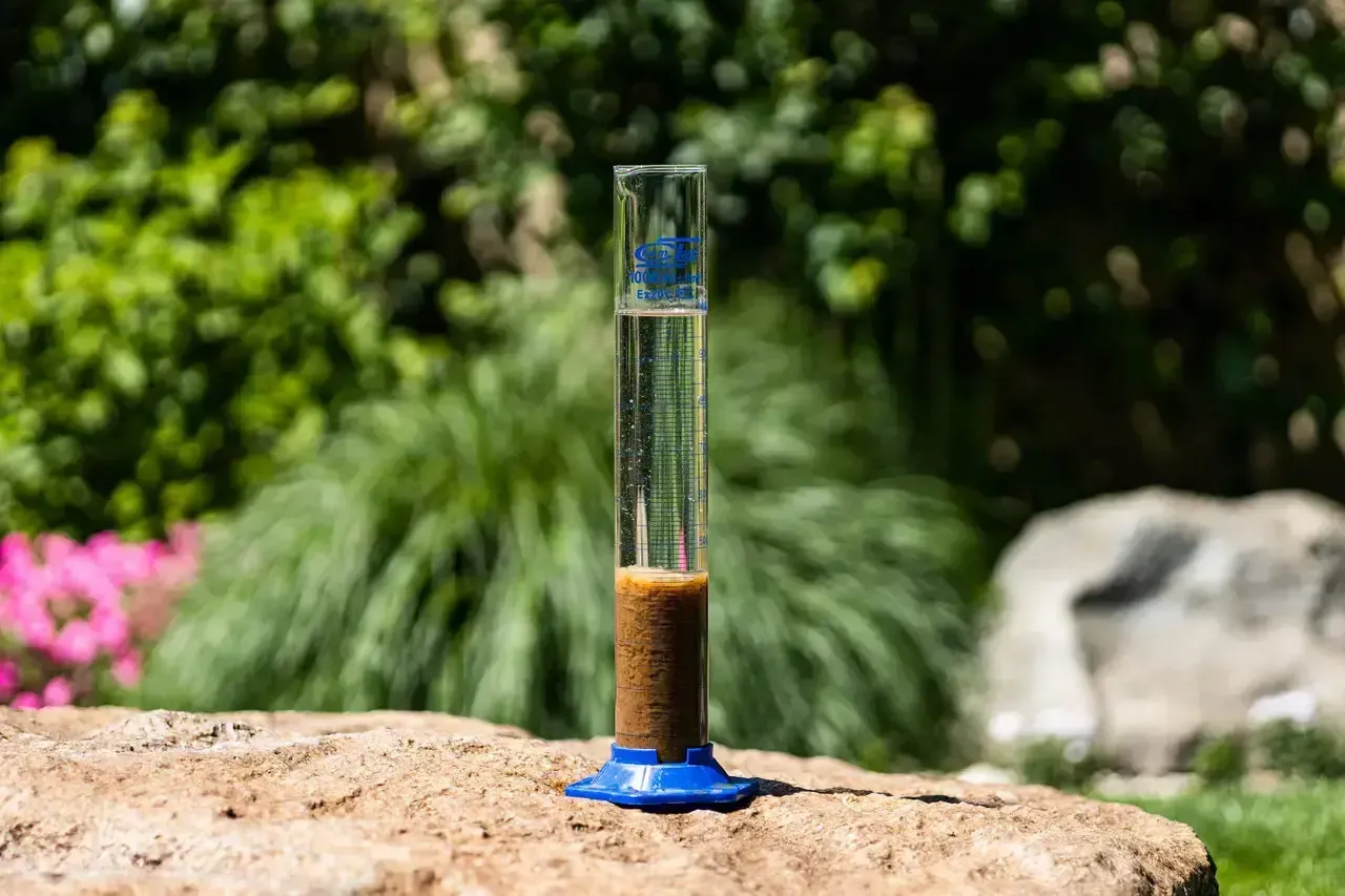 Próbówka z osadem i wodą, kluczowa do zrozumienia, jak ustawić napowietrzanie oczyszczalni.