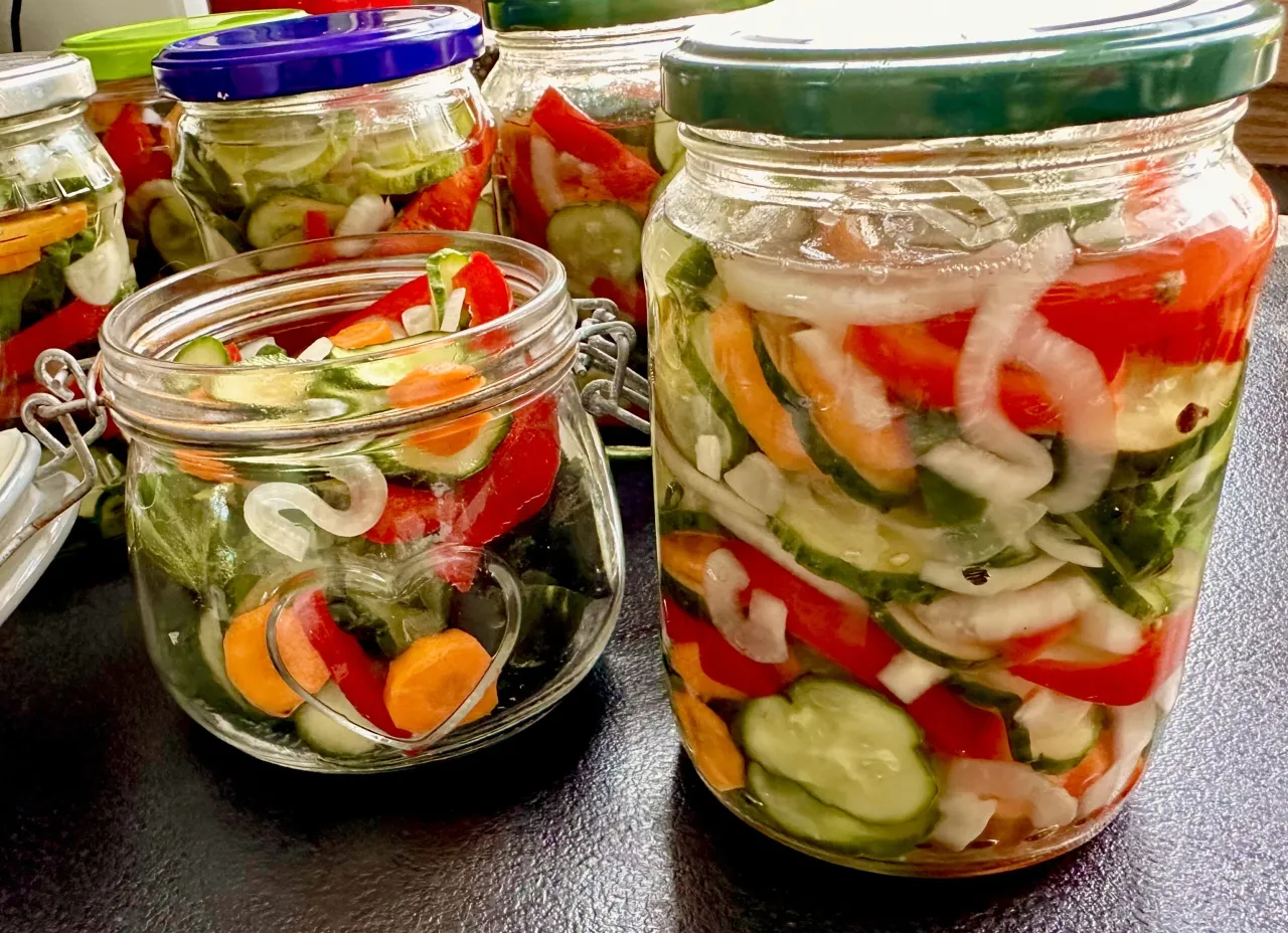 Słoiki z ogórkami, papryką i cebulą, gotowe do pasteryzacji. Czas pasteryzacji sałatki z ogórków zależy od metody.
