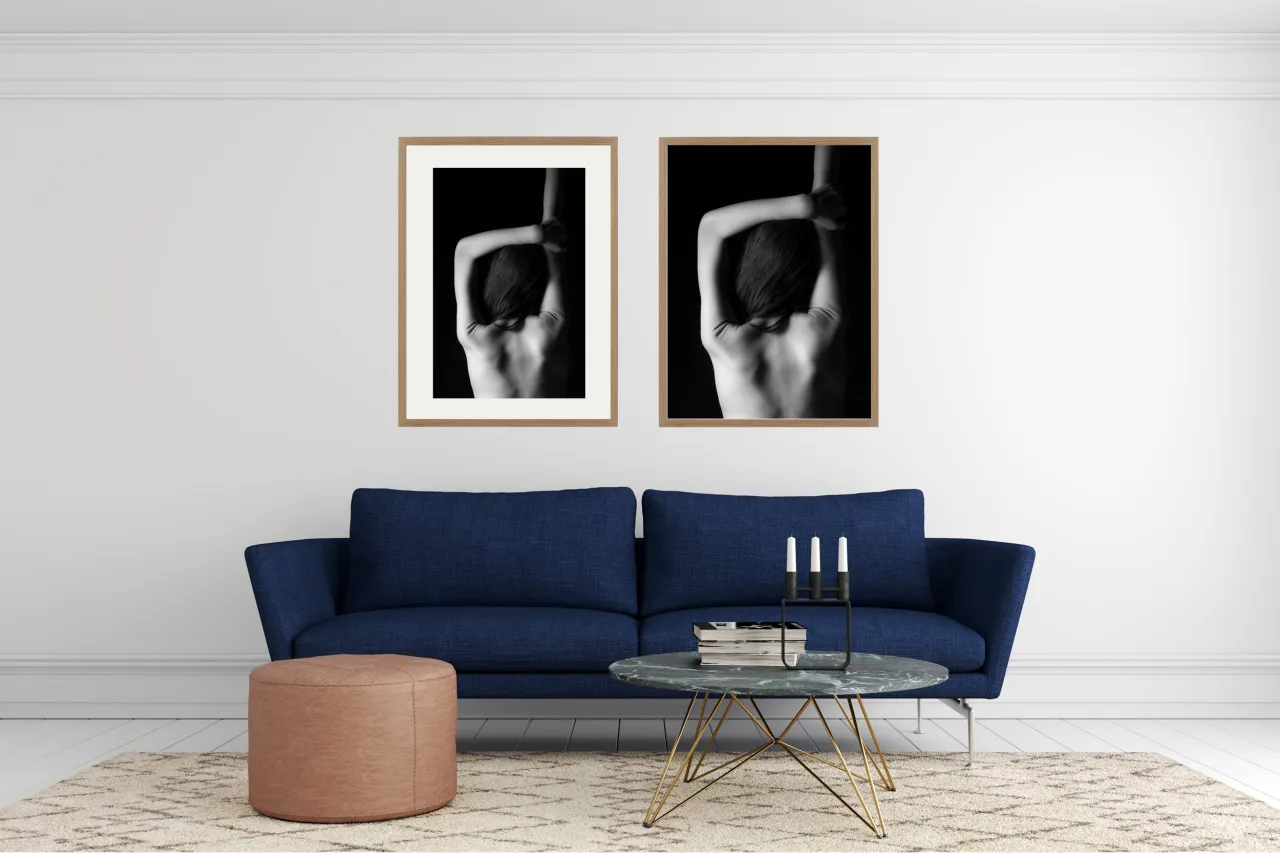 Dwa czarno-białe portrety w drewnianych ramach, wiszące nad granatową kanapą. R&oacute;żne rodzaje ram podkreślają artystyczny charakter wnętrza.