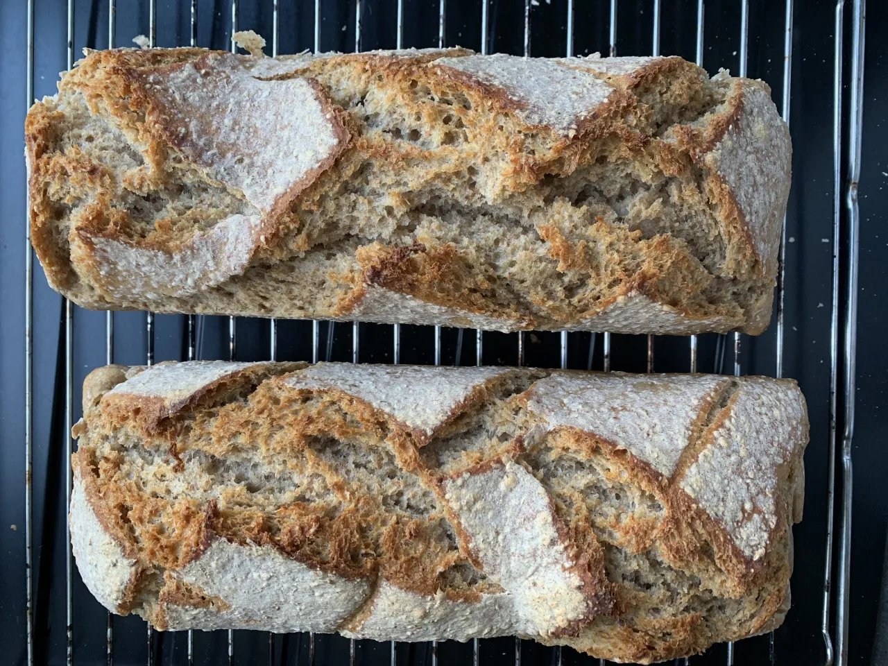 Dwa świeżo upieczone bochenki chleba na ruszcie. Idealne, gdy zastanawiasz się, jak upiec chleb dietetyczny.