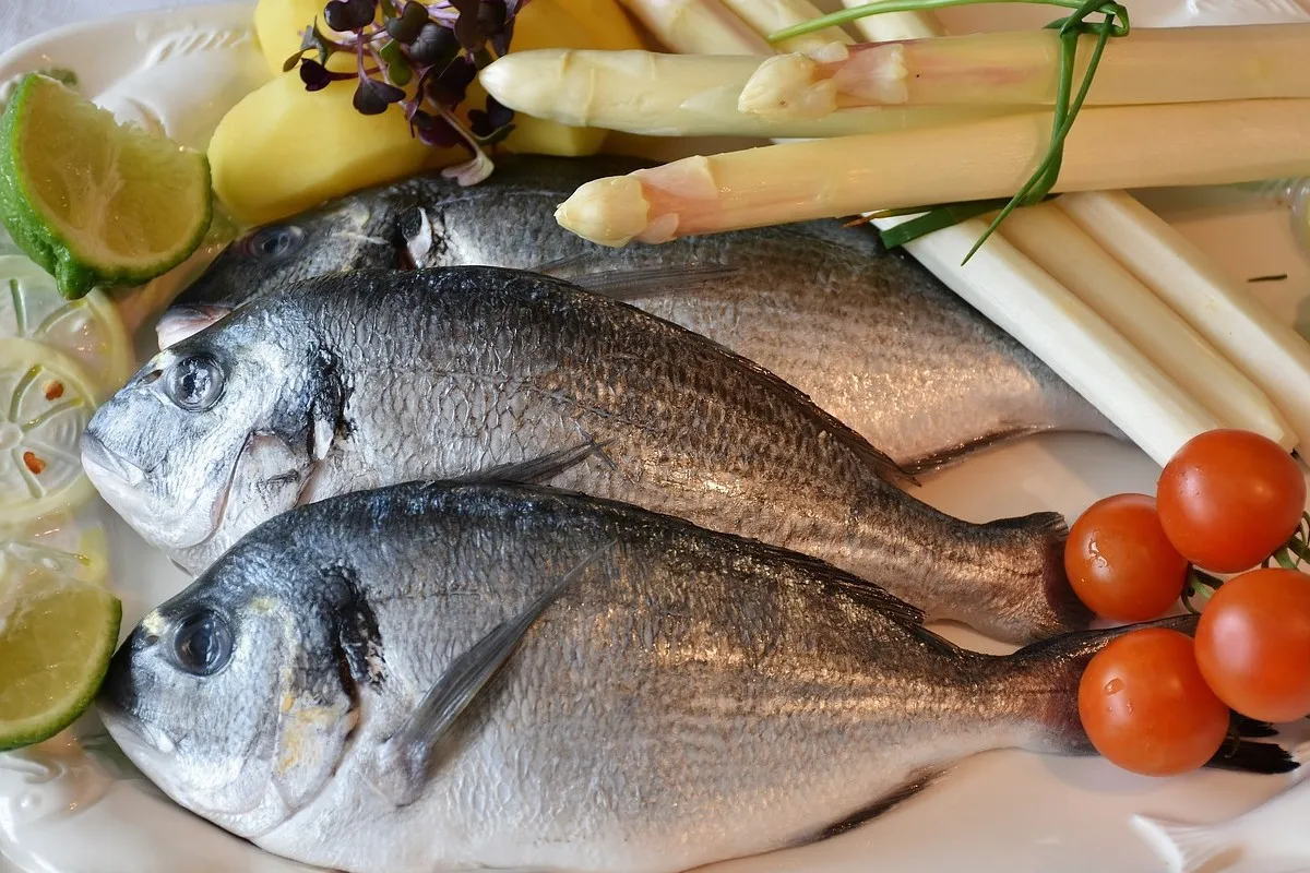 Świeże ryby z cytryną, pomidorkami i szparagami. Idealne składniki, by zastanowić się, jakie przyprawy do ryby będą najlepsze.
