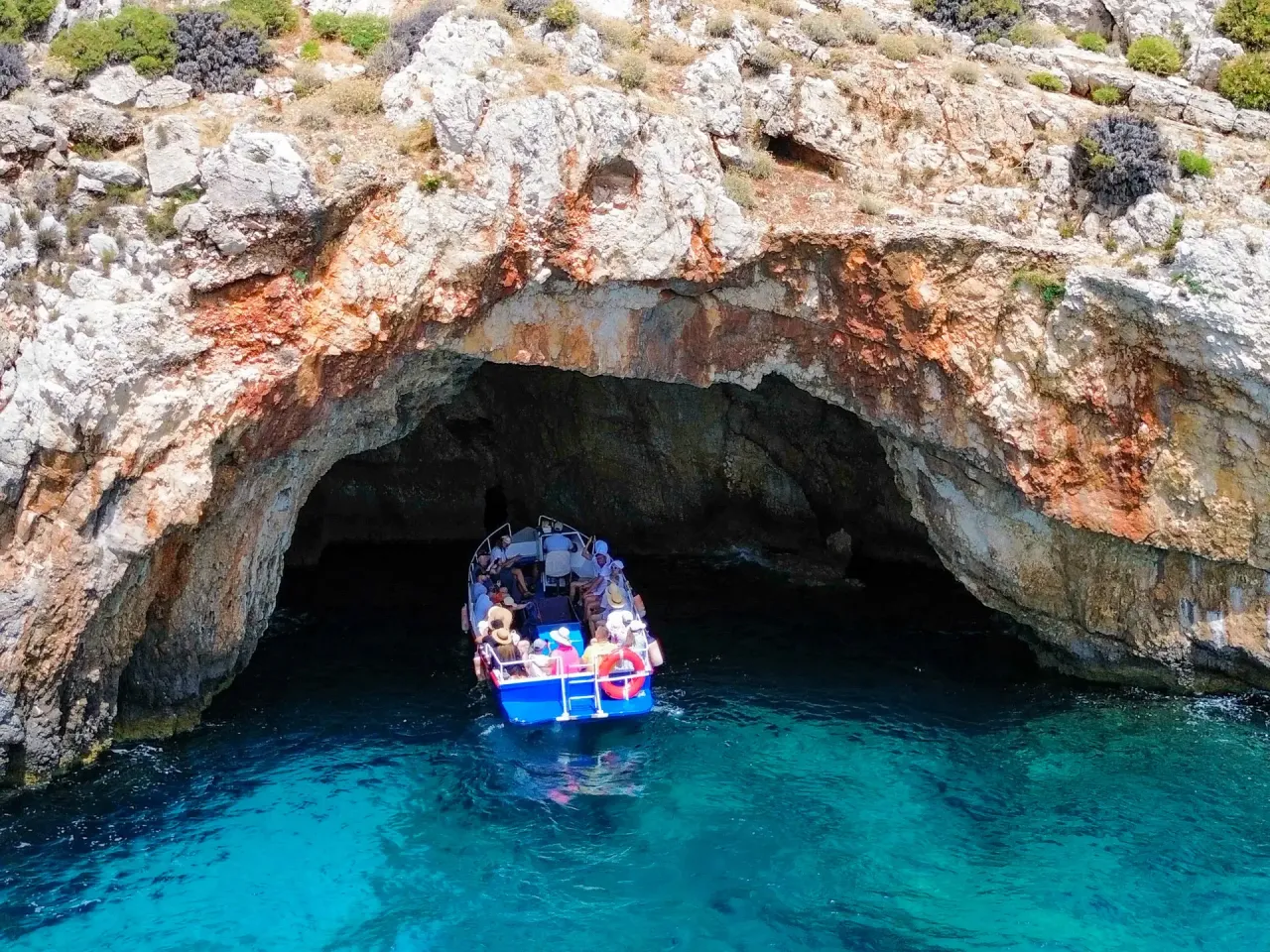 Ł&oacute;dź z turystami wpływa do jaskini na Zakynthos. To jedno z najpiękniejszych miejsc na wyspie, gdzie turkusowa woda spotyka się ze skalnymi formacjami.
