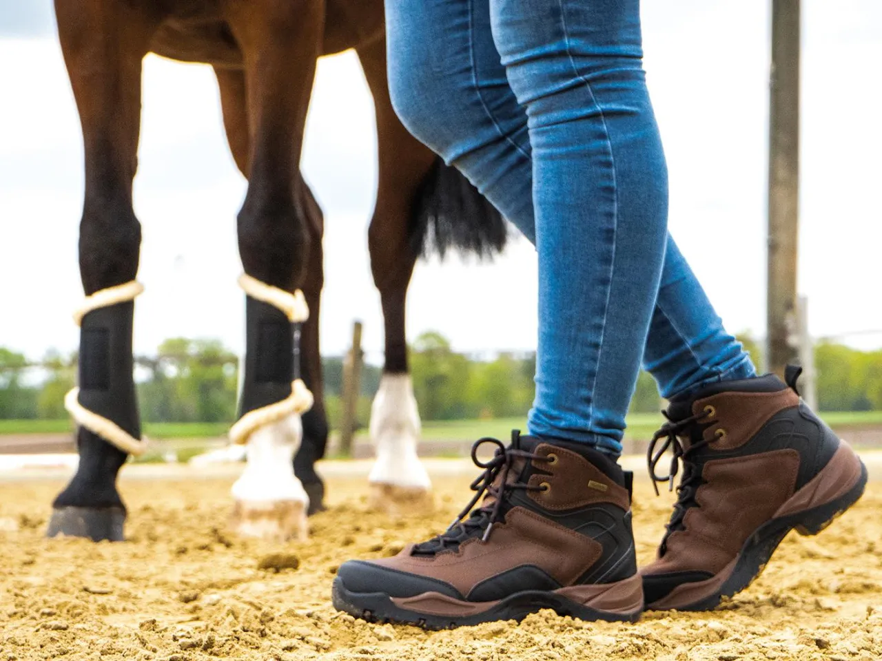 Brązowe buty jeździeckie i koń w tle. Gotowi na przejażdżkę po piasku.