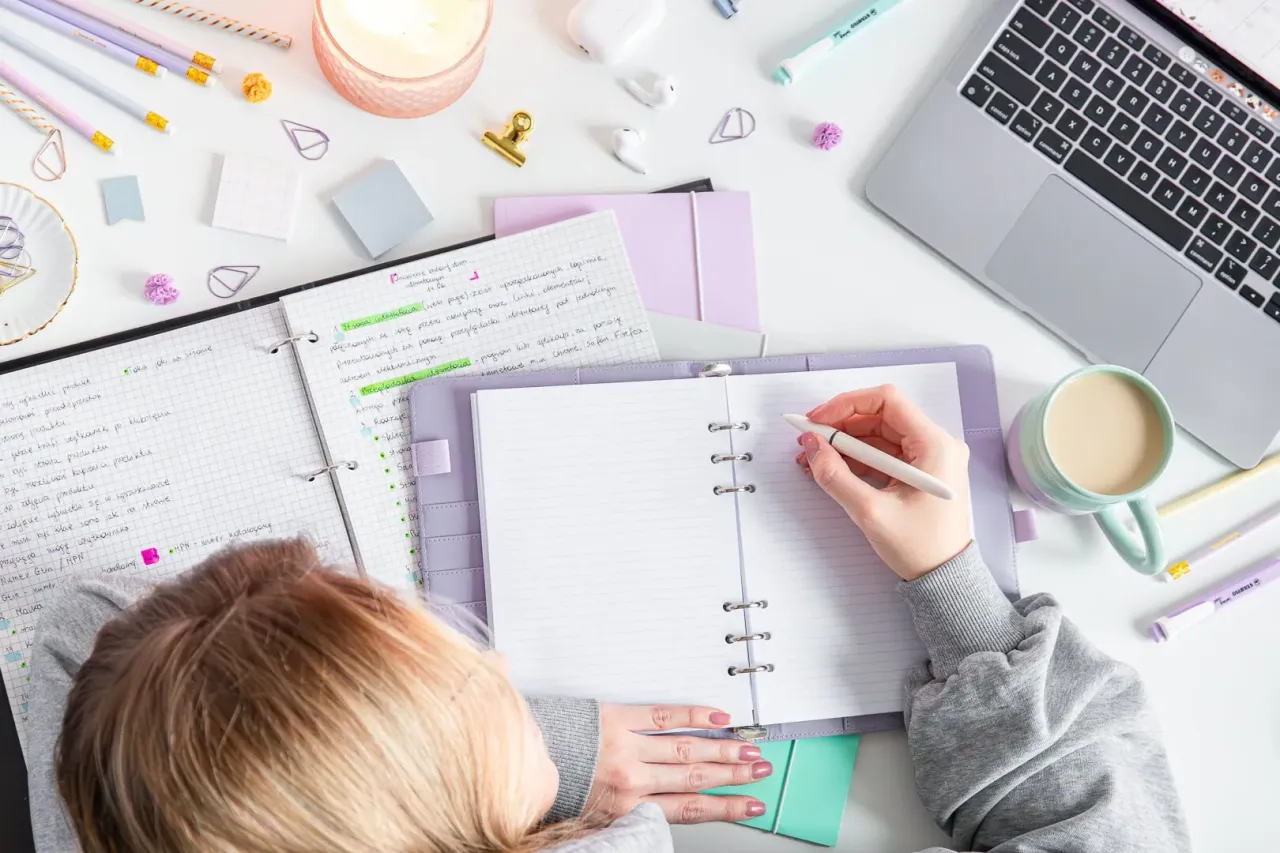 Osoba planująca rozw&oacute;j osobisty z notatnikiem i długopisem