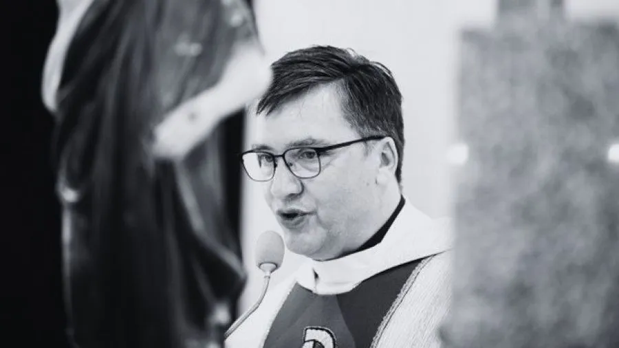 ksiądz przy biurku z dokumentami finansowymi