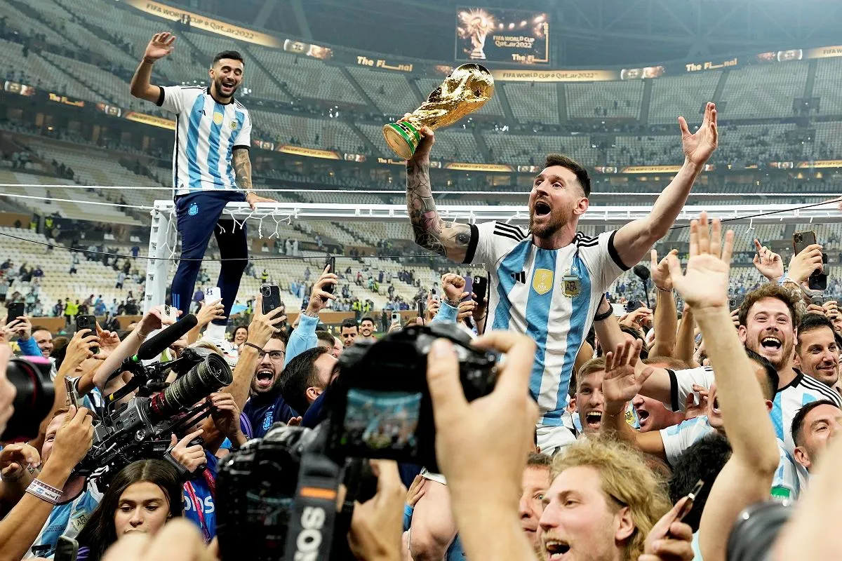 Leo Messi, kto jest mistrzem świata w piłce nożnej, świętuje z pucharem i kibicami.