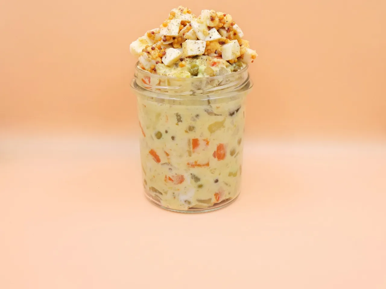 Sałatka jarzynowa z jogurtem w słoiku, z jajkiem i musztardą na wierzchu. Zastanawiasz się, ile kalorii ma sałatka jarzynowa z jogurtem?