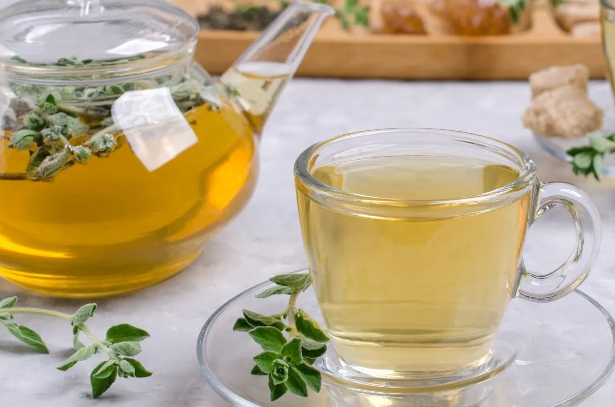 Zaparzona herbata z oregano w szklanym dzbanku i filiżance. Napar z oregano wspiera odporność i działa przeciwzapalnie.