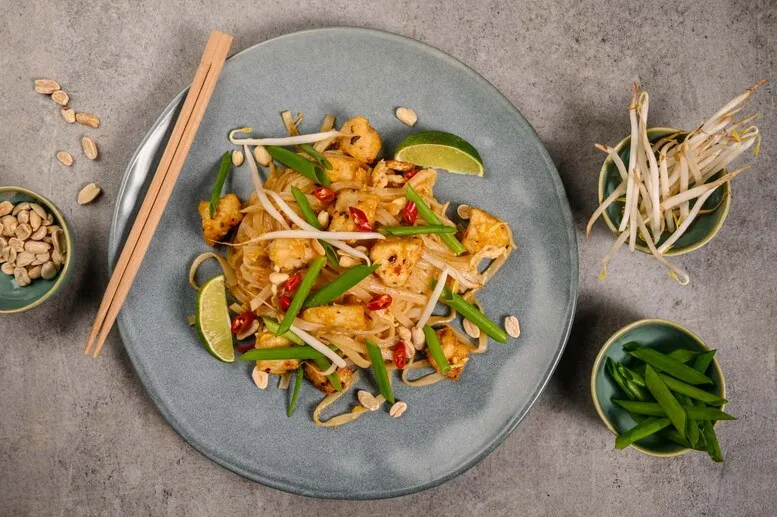 osoba mieszająca Pad Thai z dodatkami