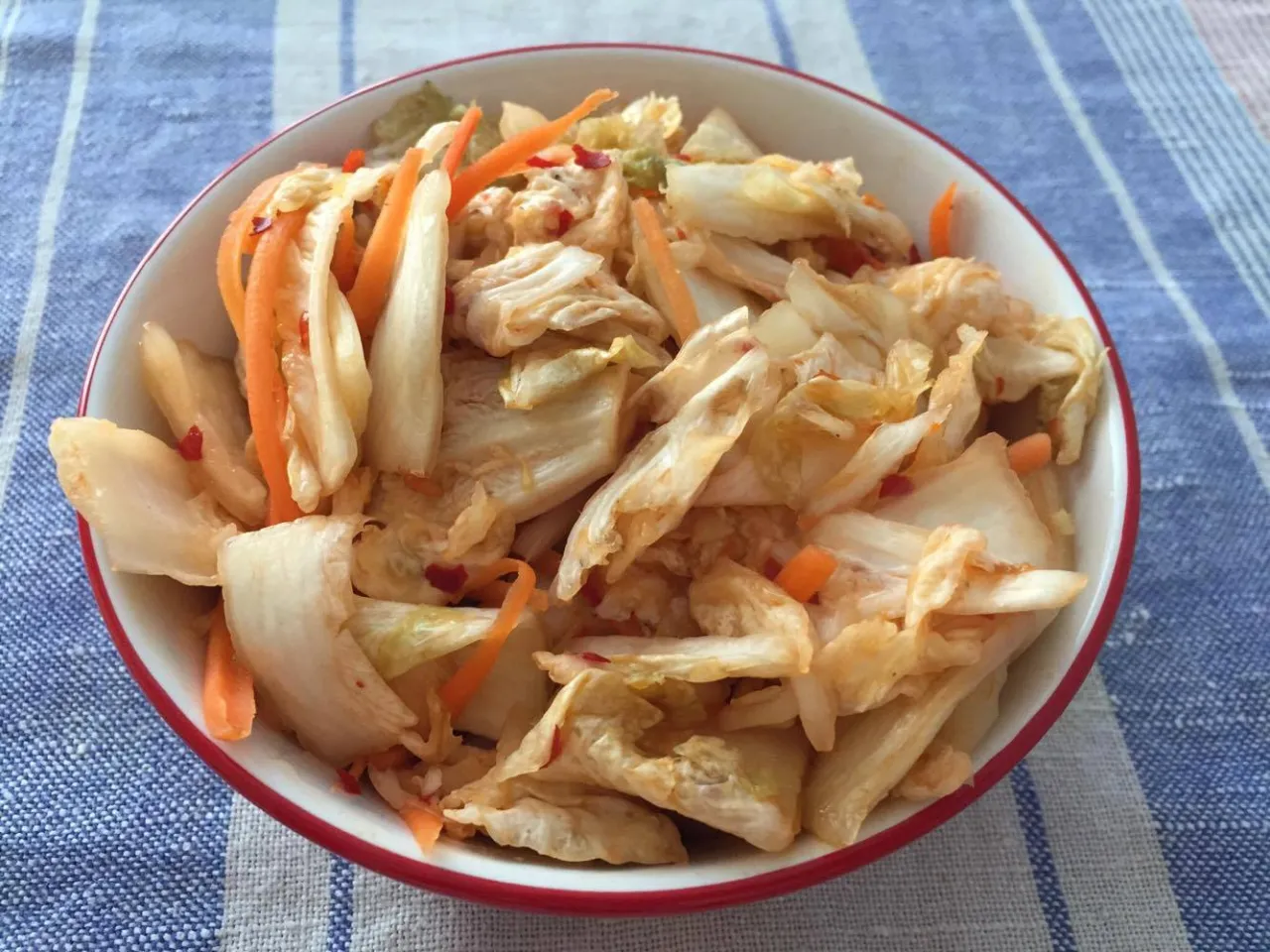 Miseczka pełna pikantnej sałatki kim chi z kapusty pekińskiej i marchewki, gotowa do podania.