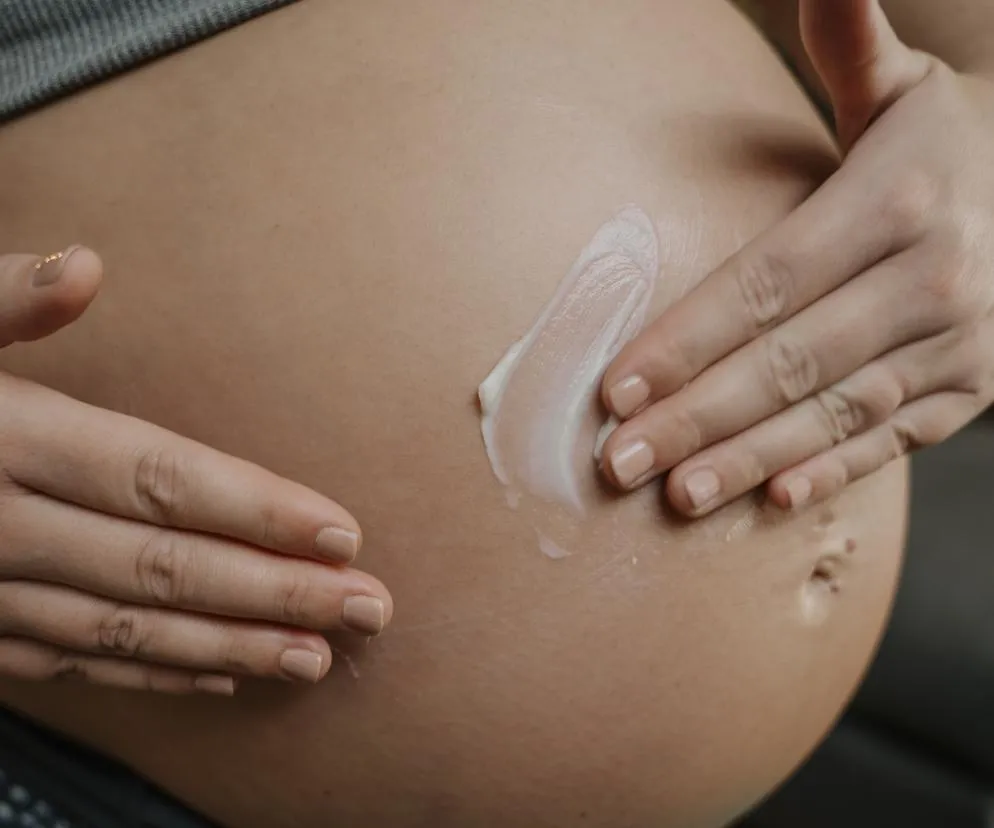 kobieta w ciąży smarująca brzuch