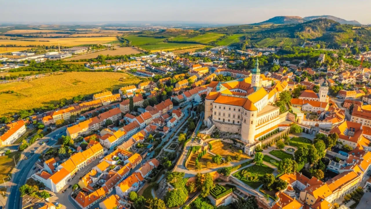 Widok z lotu ptaka na Mikulov, jedno z najpiękniejszych miast Czech, z zamkiem g&oacute;rującym nad kolorowymi dachami i zielonymi wzg&oacute;rzami w tle.