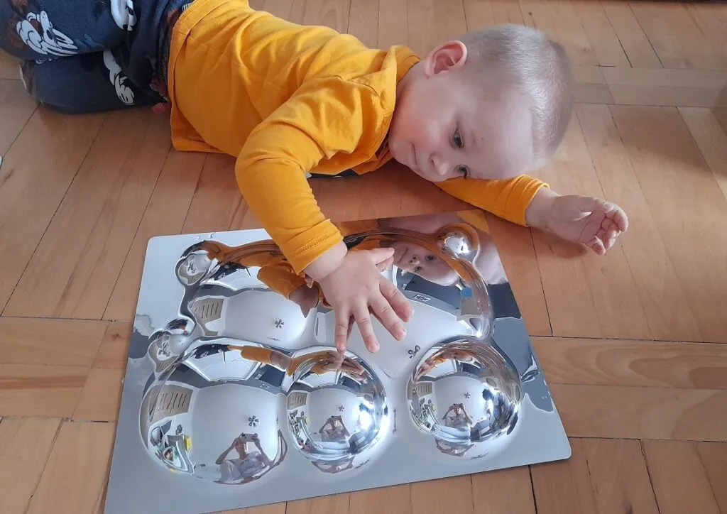 niemowlę bawiące się lusterkiem sensorycznym na macie