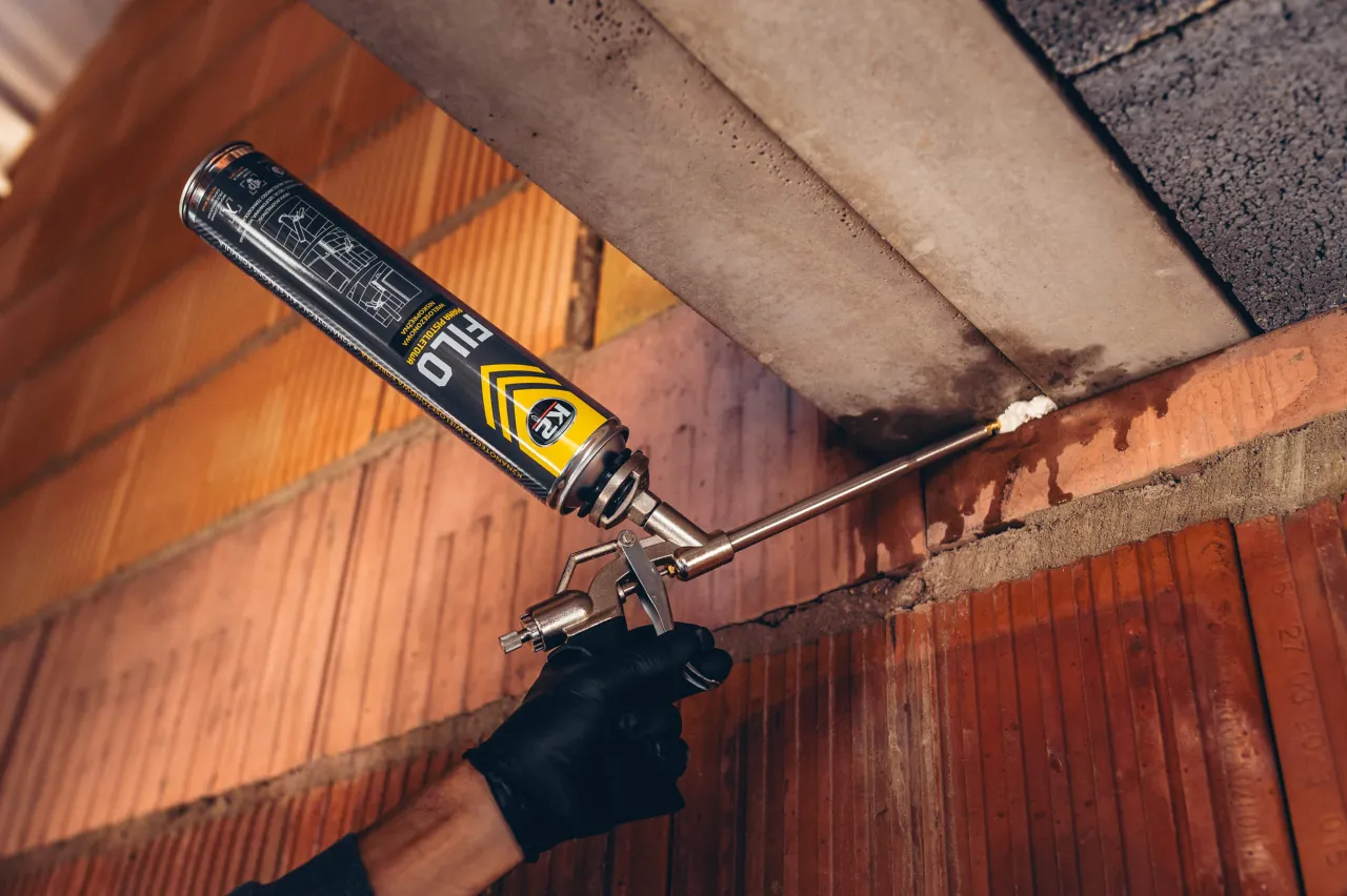 Rękawica z pistoletem pianotwórczym aplikuje piankę montażową, idealną do tego, czym uszczelnić drzwi.