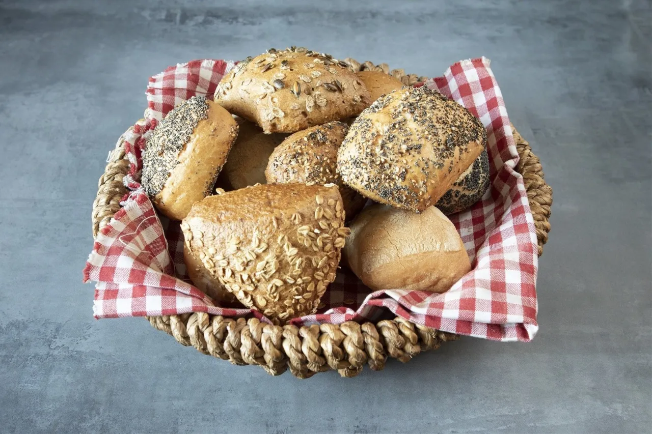 Koszyk pełen świeżych bułek, w tym grahamek posypanych ziarnami. Zastanawiasz się, ile kalorii ma bułka grahamka?