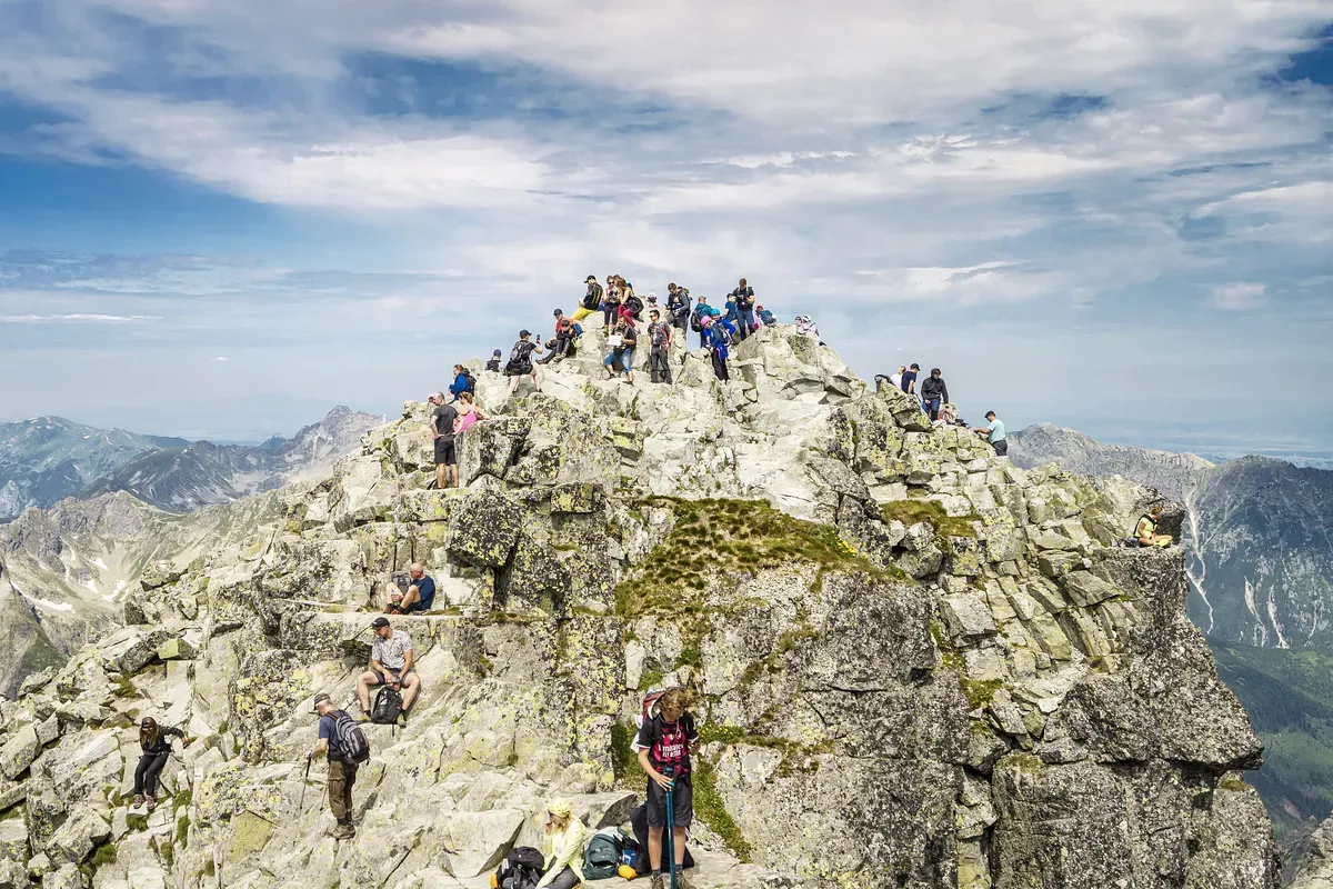 Tłum turyst&oacute;w na szczycie Rys&oacute;w. Ile czasu zajmuje wejście? Widok na Tatry.